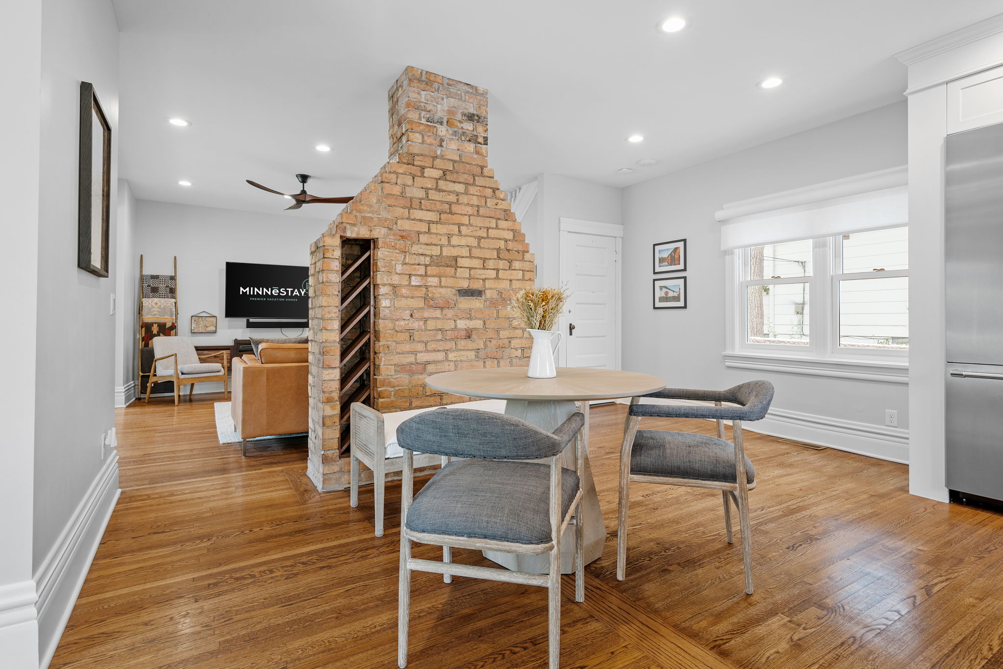 Modern and inviting open living space with a dining area and brick fireplace.
