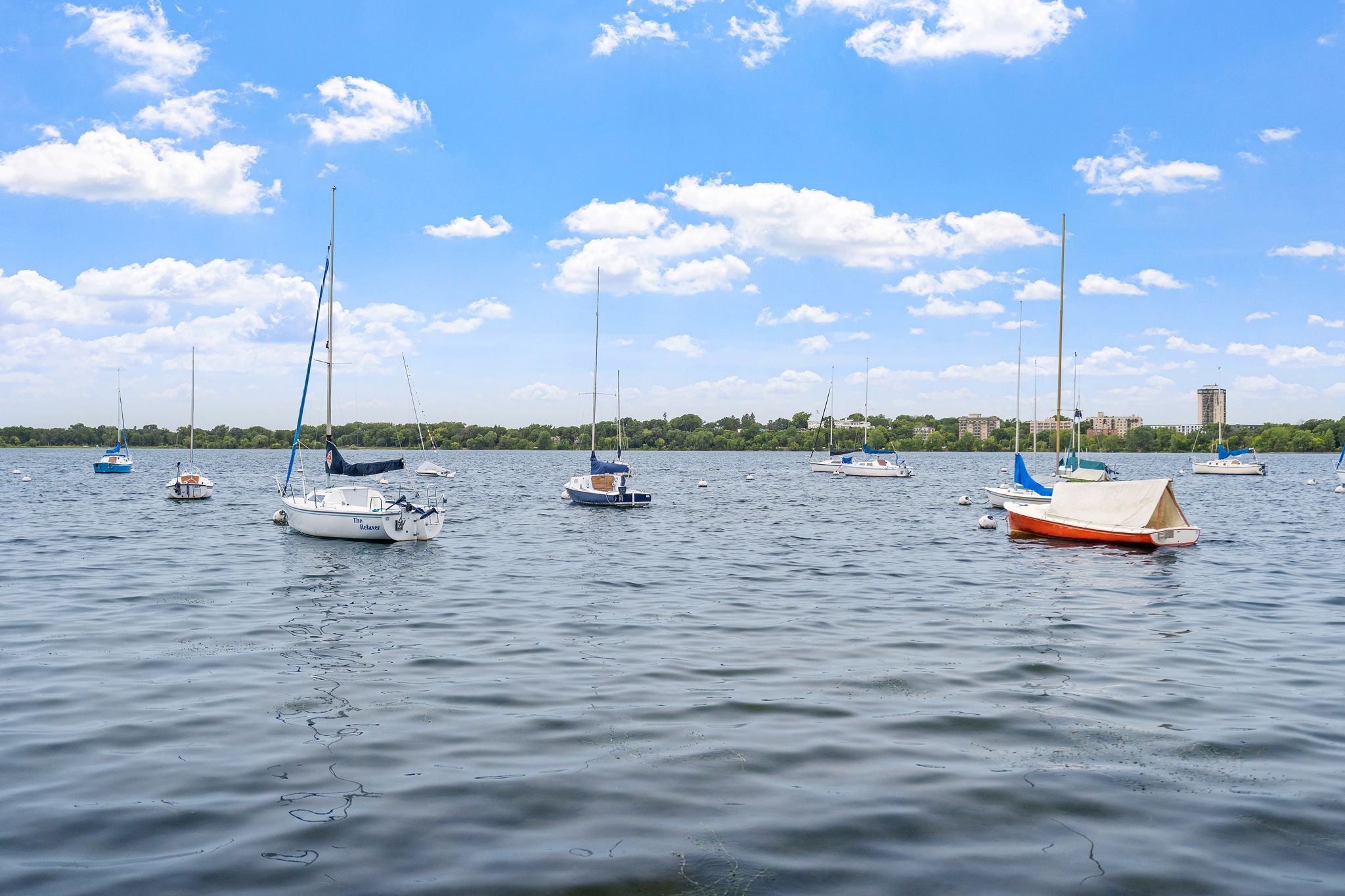 Sailboats floating on a tranquil lake under a bright blue sky.