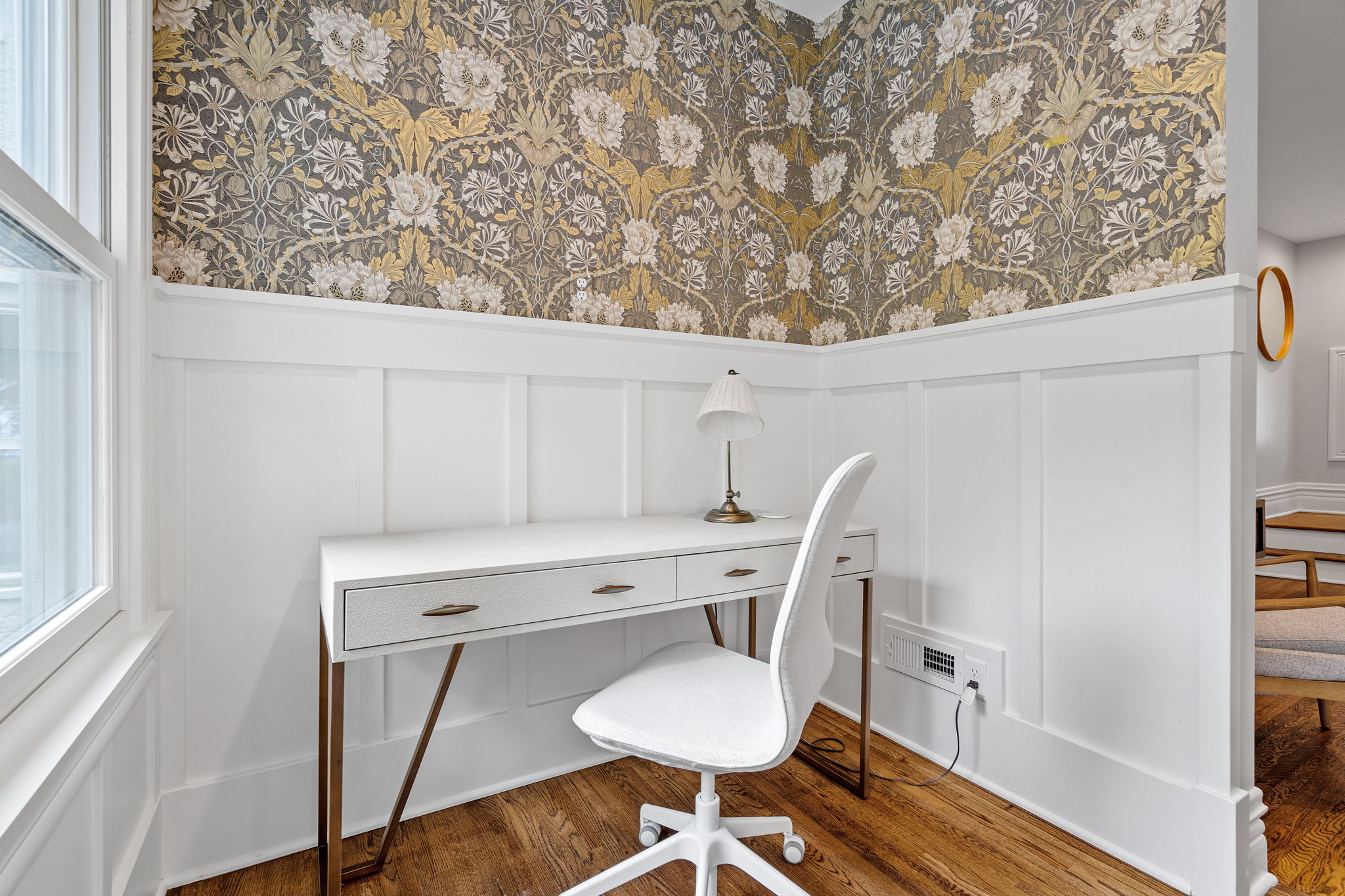 A cozy home office corner with a modern desk and elegant floral wallpaper.