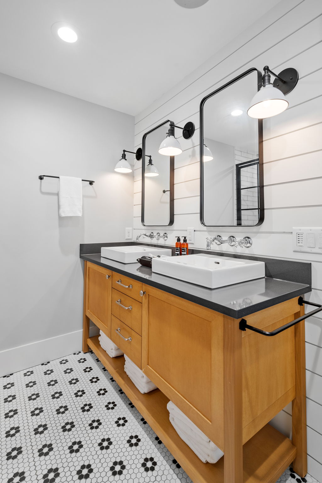 A modern bathroom featuring a stylish wooden vanity, sleek sinks, and elegant lighting.