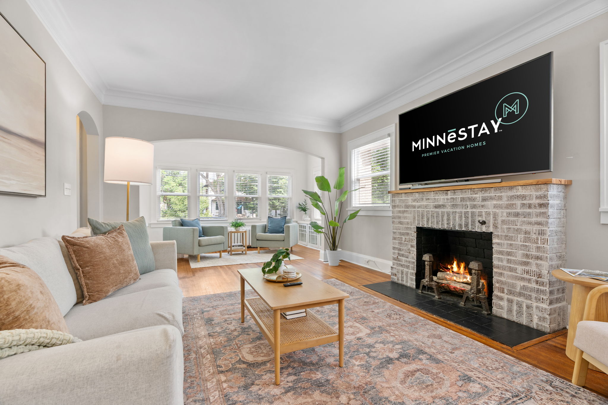 Living room with a fireplace, comfortable seating, and a TV displaying MINNESTAY logo.