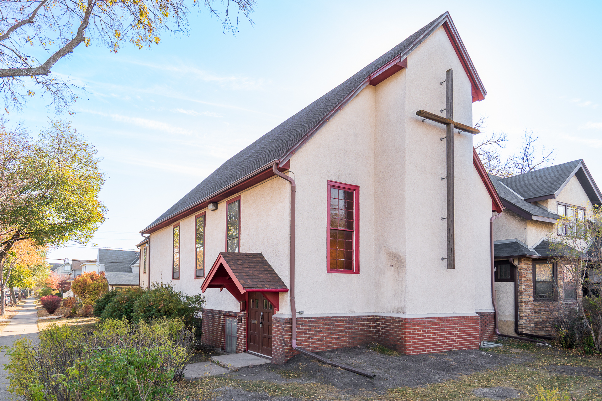A charming church with a wooden cross and vibrant red trim.