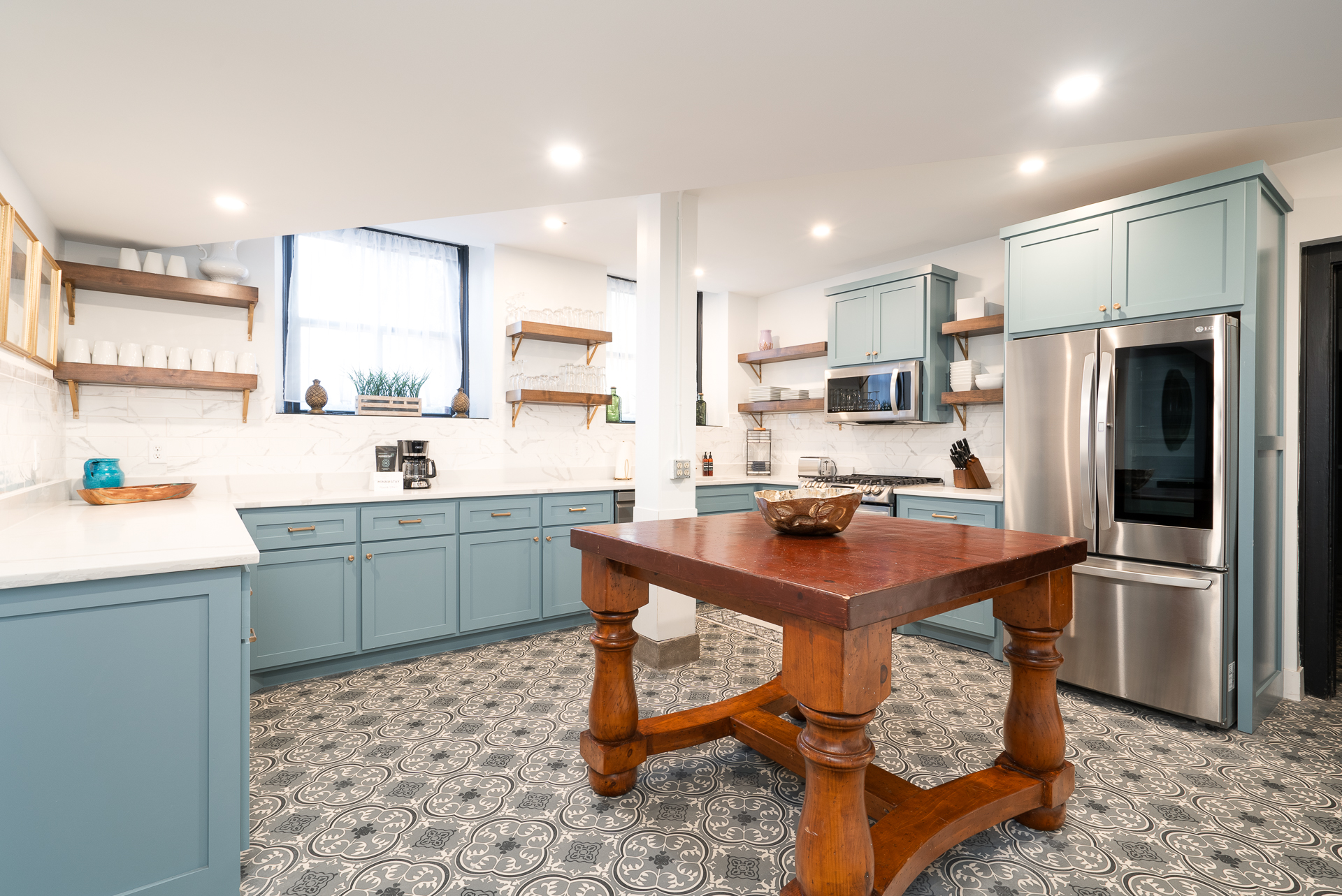 A stylish modern kitchen with blue cabinetry and a rustic wooden table.