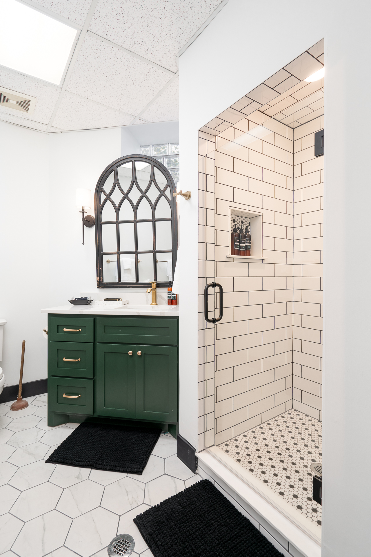 Stylishly designed bathroom featuring a green vanity and an arched mirror.