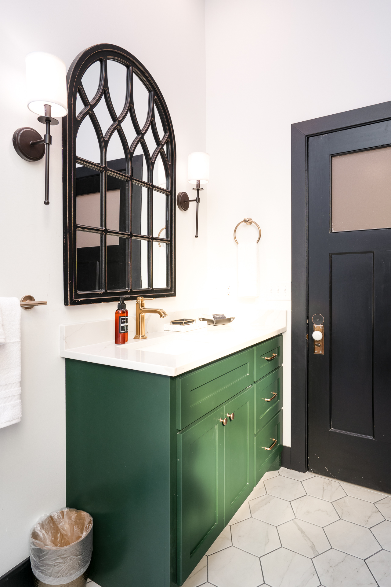 Elegant modern bathroom with deep green vanity and Gothic-style mirror.