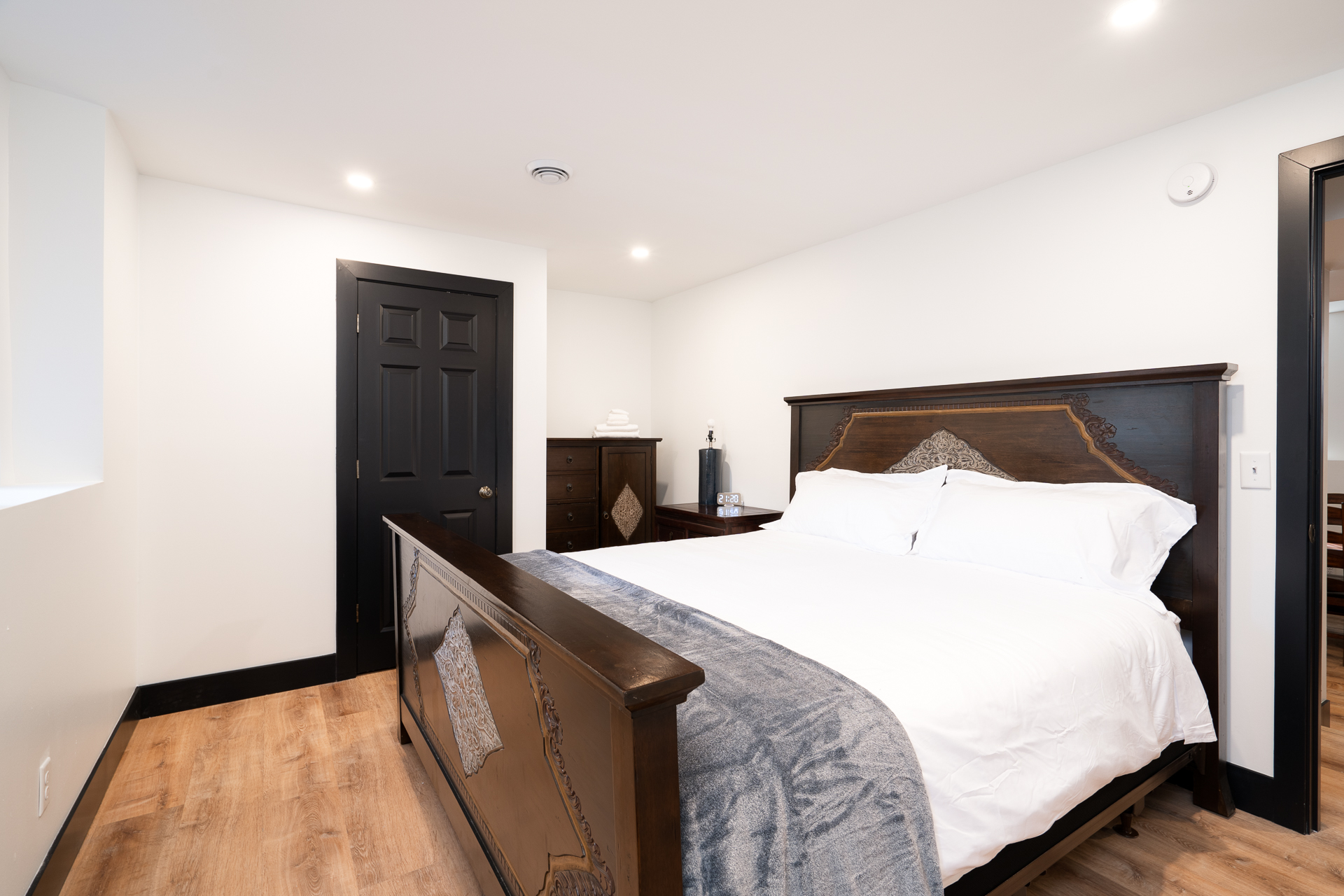 A modern minimalistic bedroom featuring a large bed with dark wooden accents.
