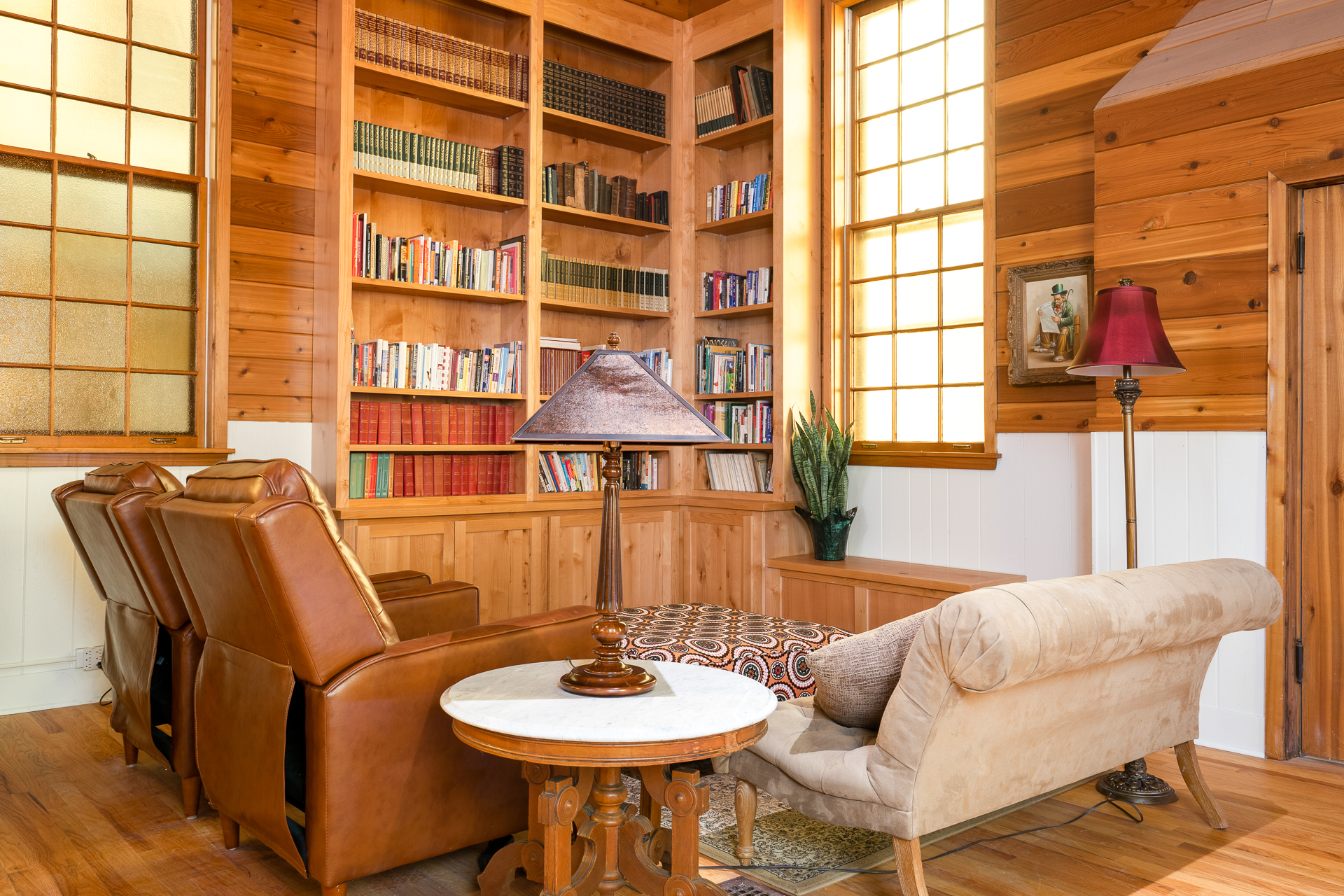 A cozy reading nook with leather armchairs and an extensive bookshelf.