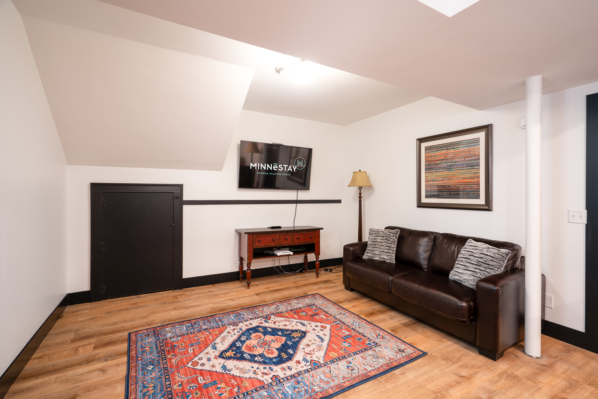 A cozy and stylish living area featuring a leather sofa, vibrant rug, and decorative art.