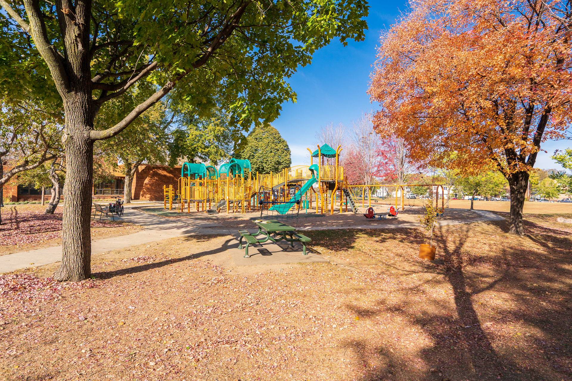 A colorful playground surrounded by vibrant autumn foliage.