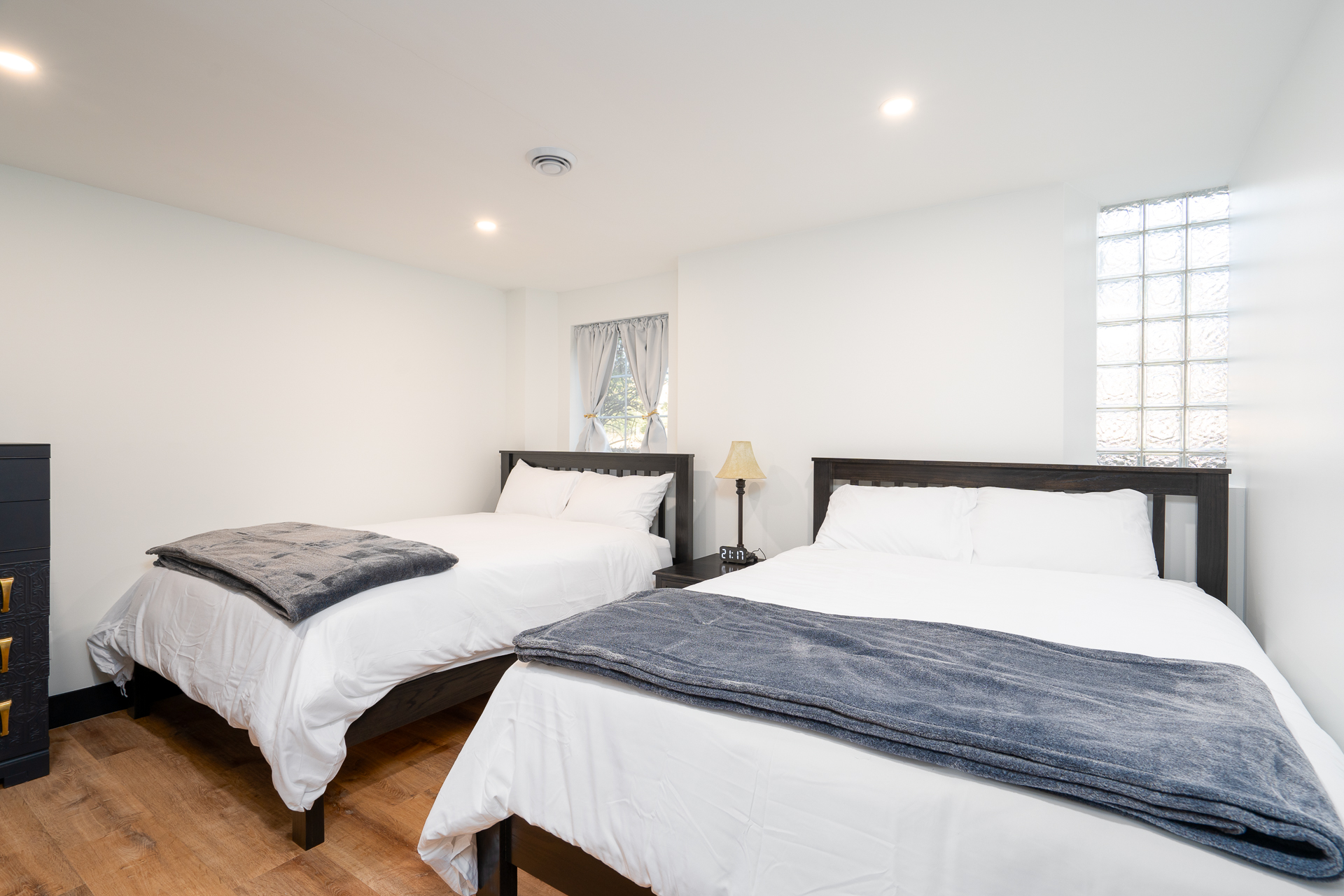 A cozy, modern bedroom featuring two beds and warm lighting.