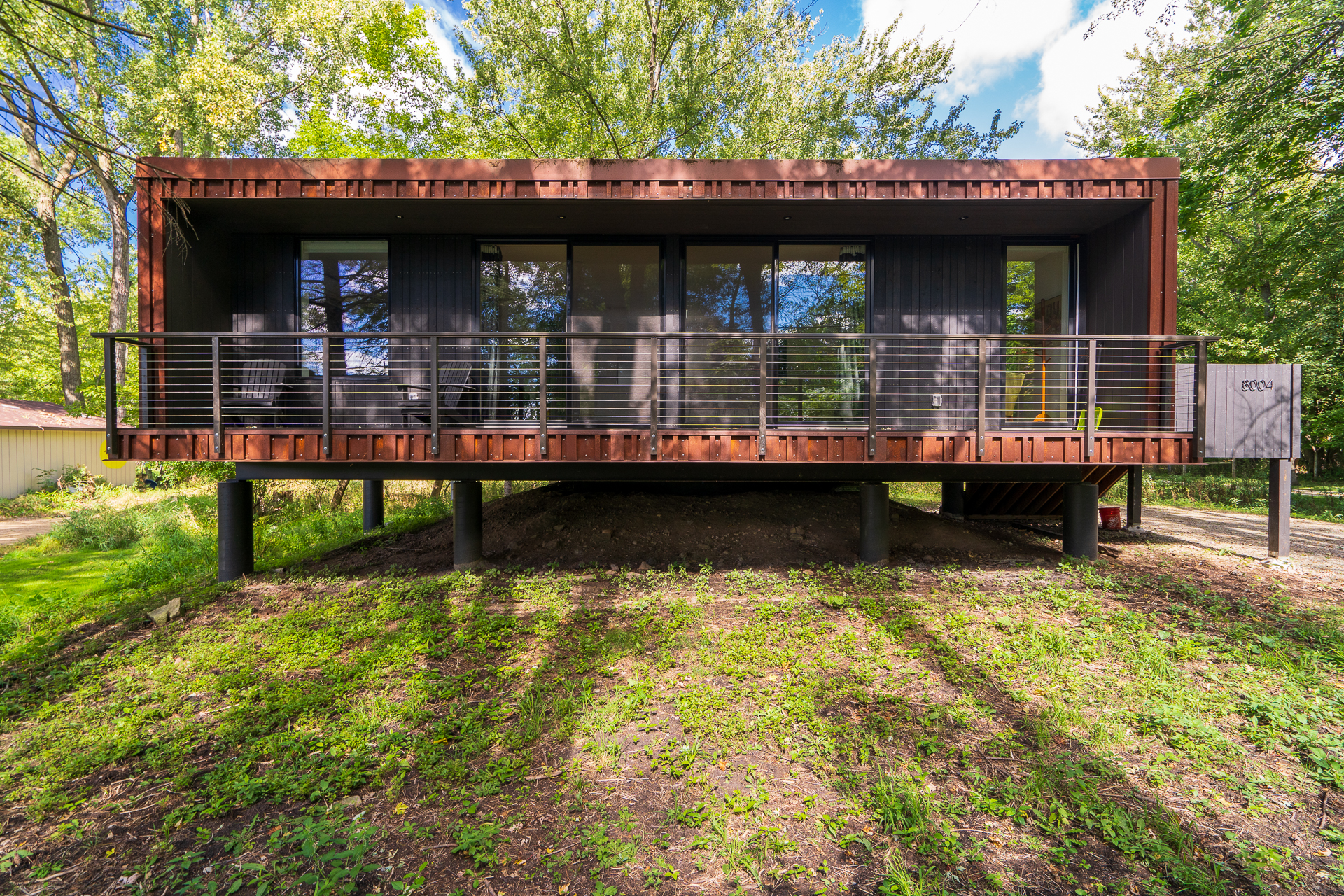 Modern elevated home surrounded by lush greenery.