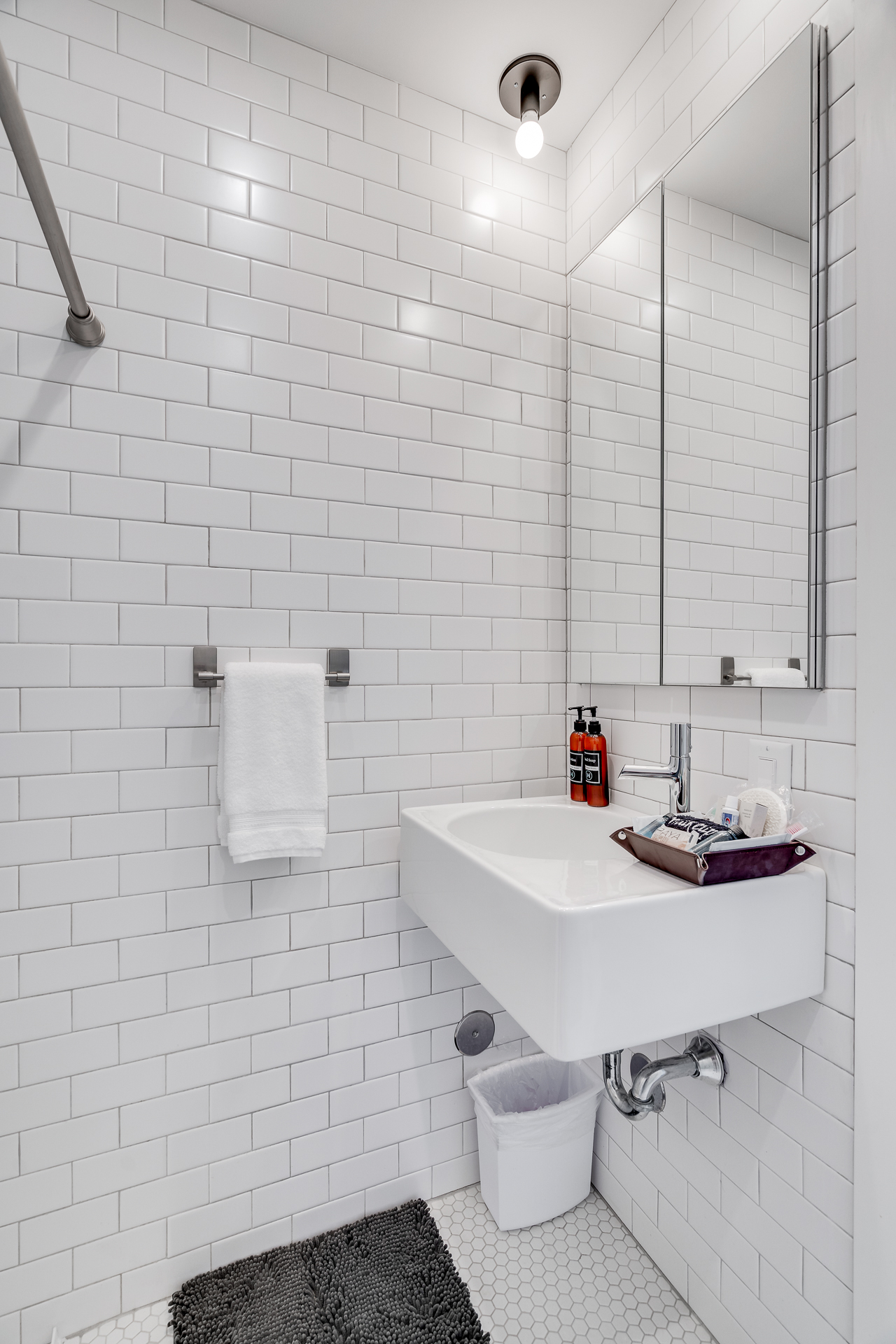 A modern bathroom featuring white subway tiles and a sleek sink with toiletries.