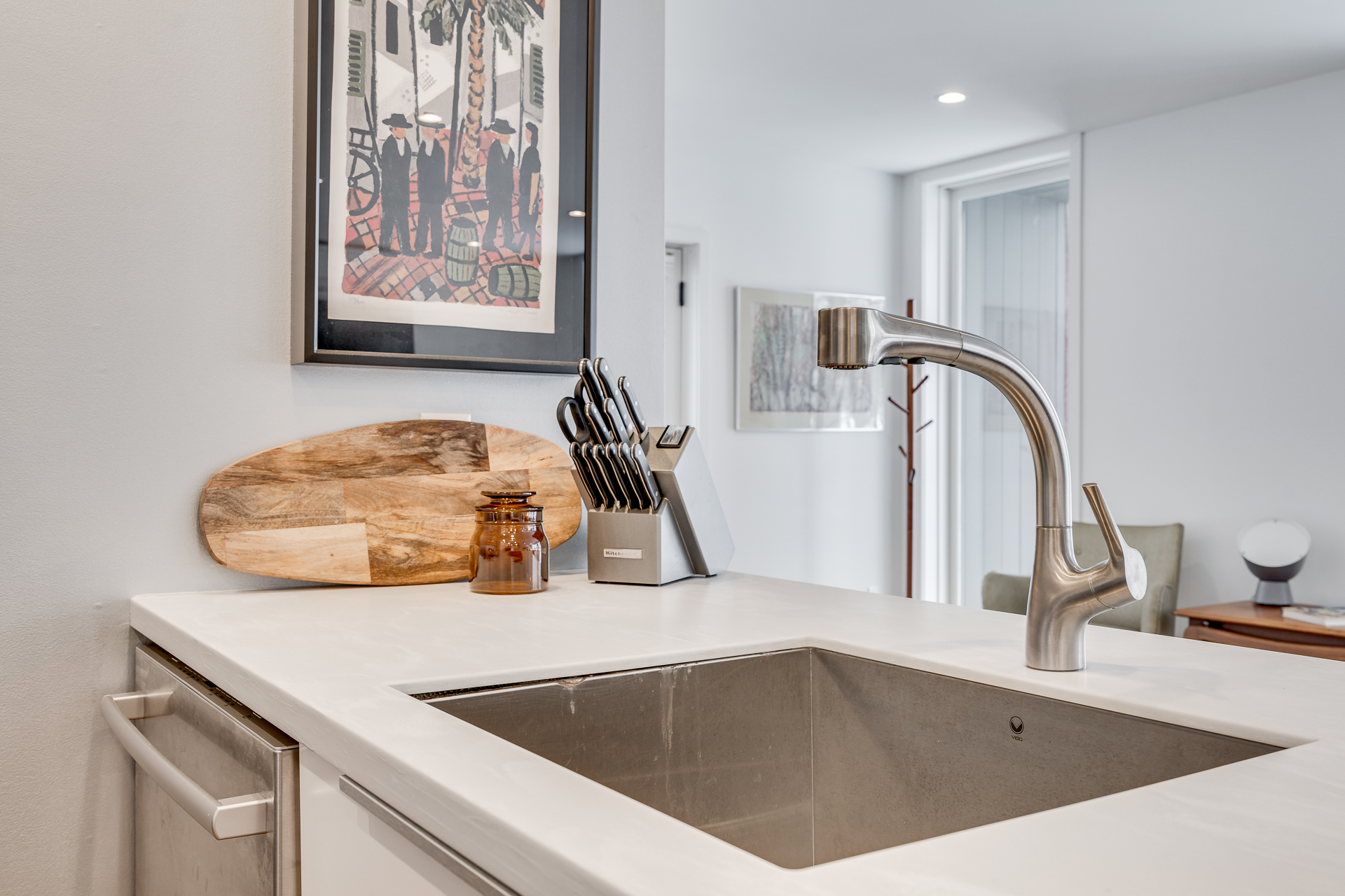 A modern kitchen featuring a stainless steel sink, a stylish faucet, and artistic decor.