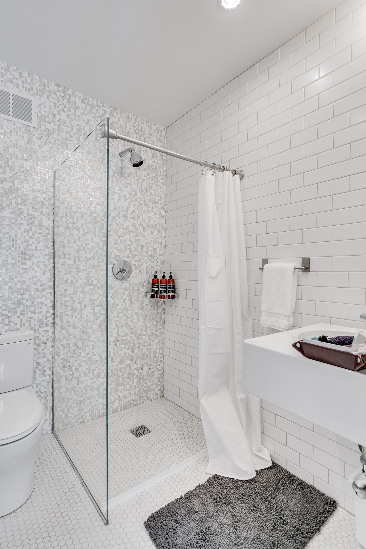 A modern bathroom featuring a glass shower, sleek fixtures, and textured tiles.