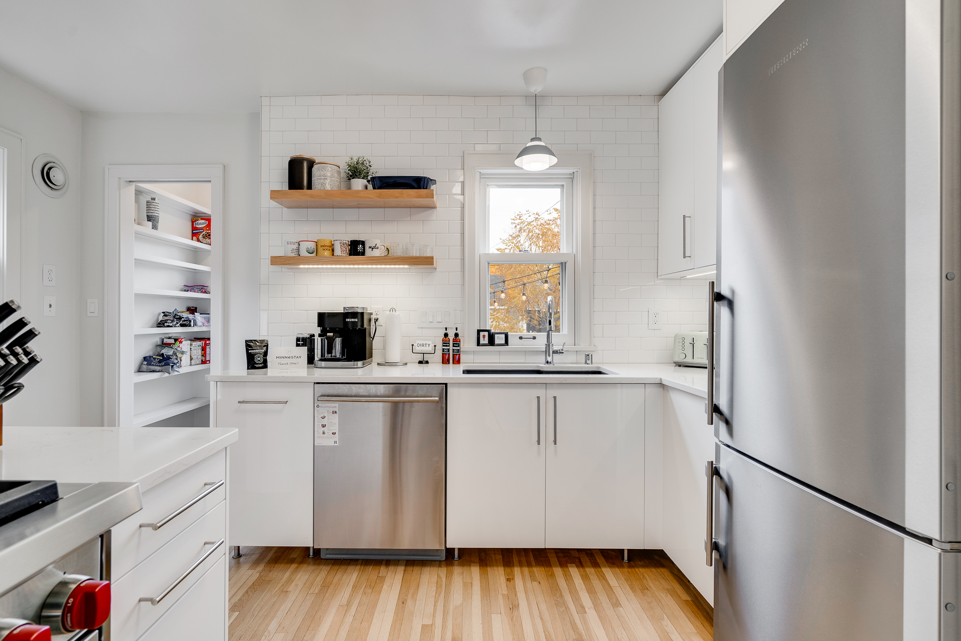 A sleek and modern kitchen with open shelving and organized pantry.