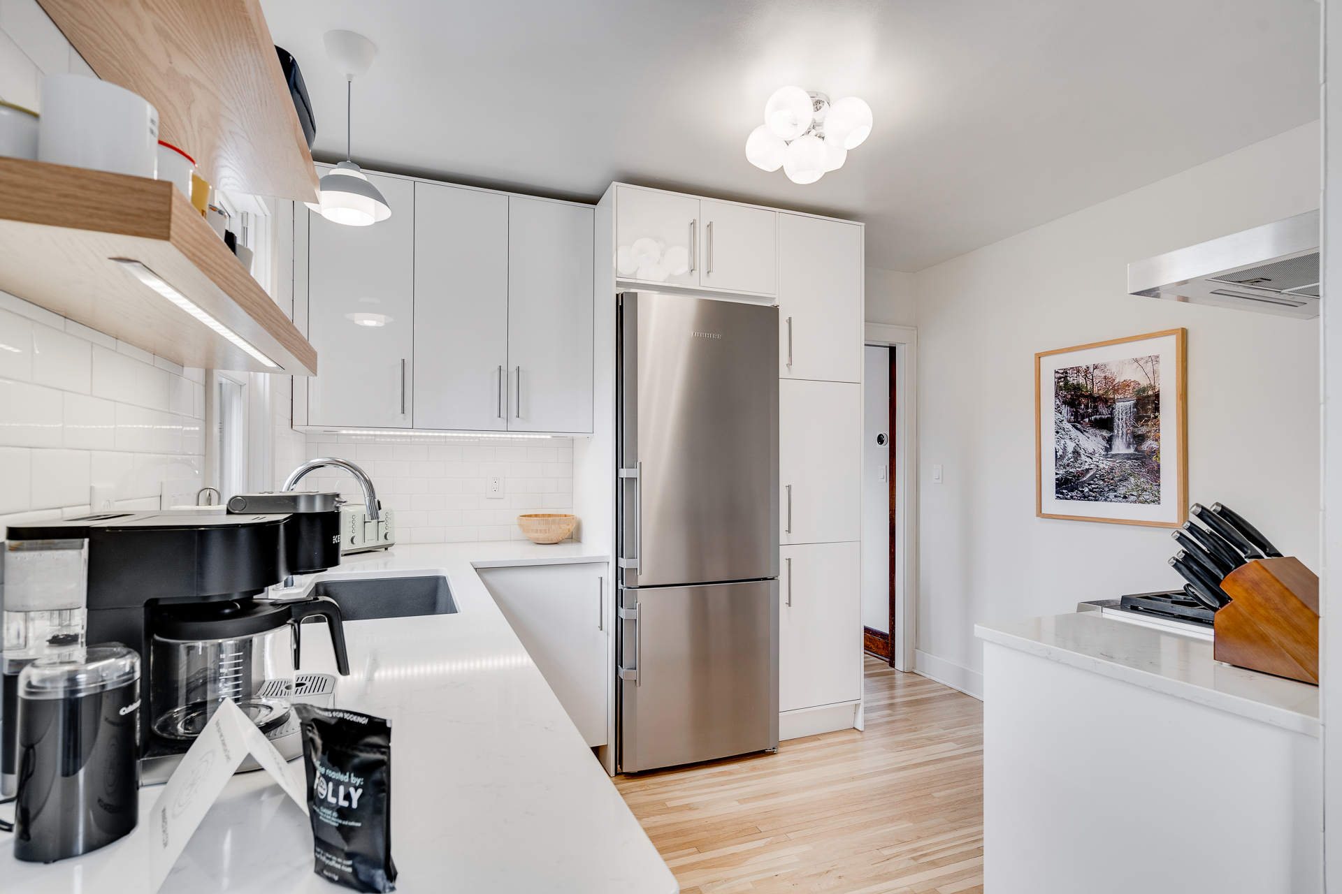 A modern kitchen featuring sleek white cabinetry and stainless steel appliances.