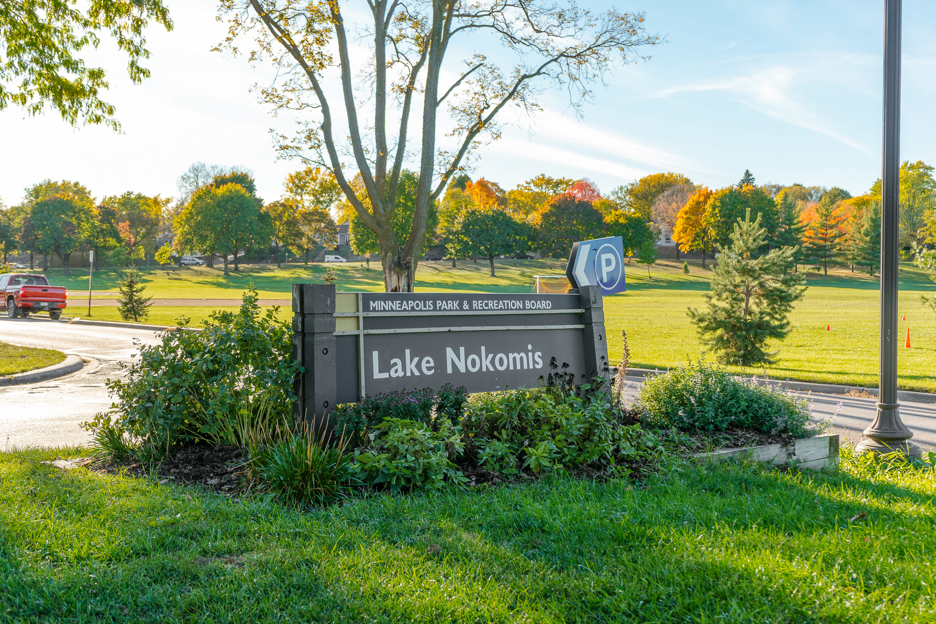 Sign for Lake Nokomis displaying autumn colors and inviting scenery.
