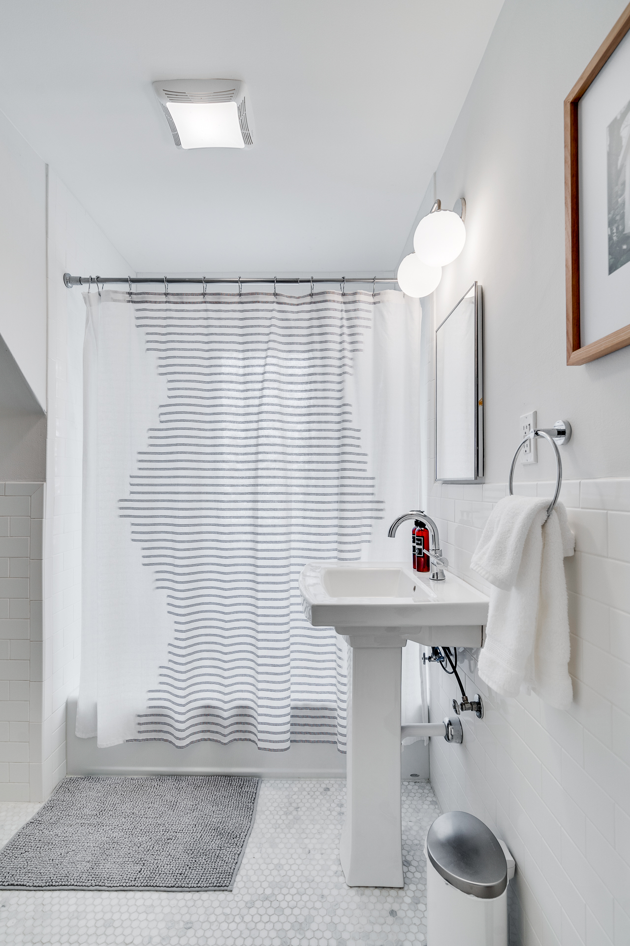 A modern bathroom featuring a stylish shower curtain and sleek pedestal sink.