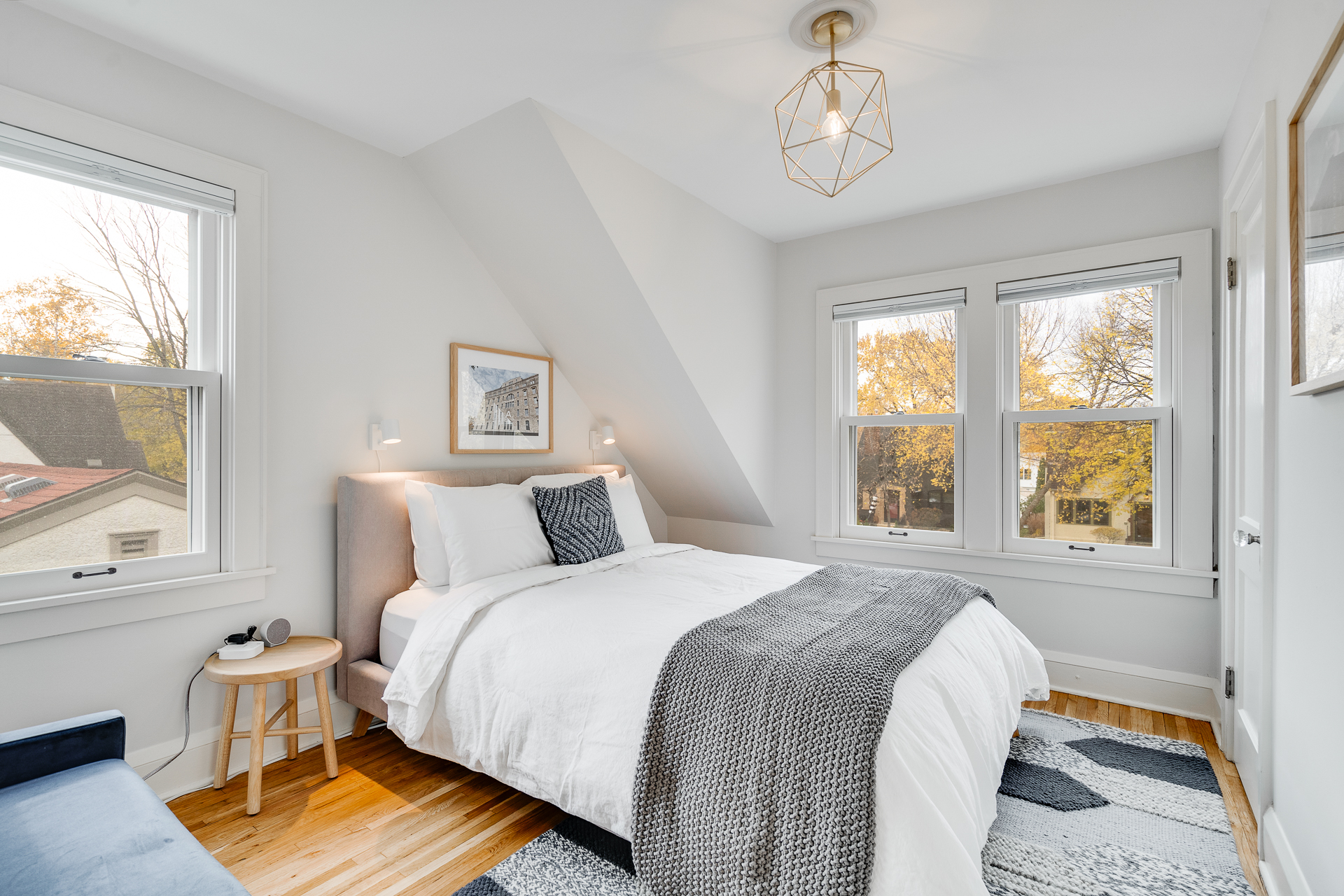 A cozy and modern bedroom highlighted by natural light and autumn colors outside.