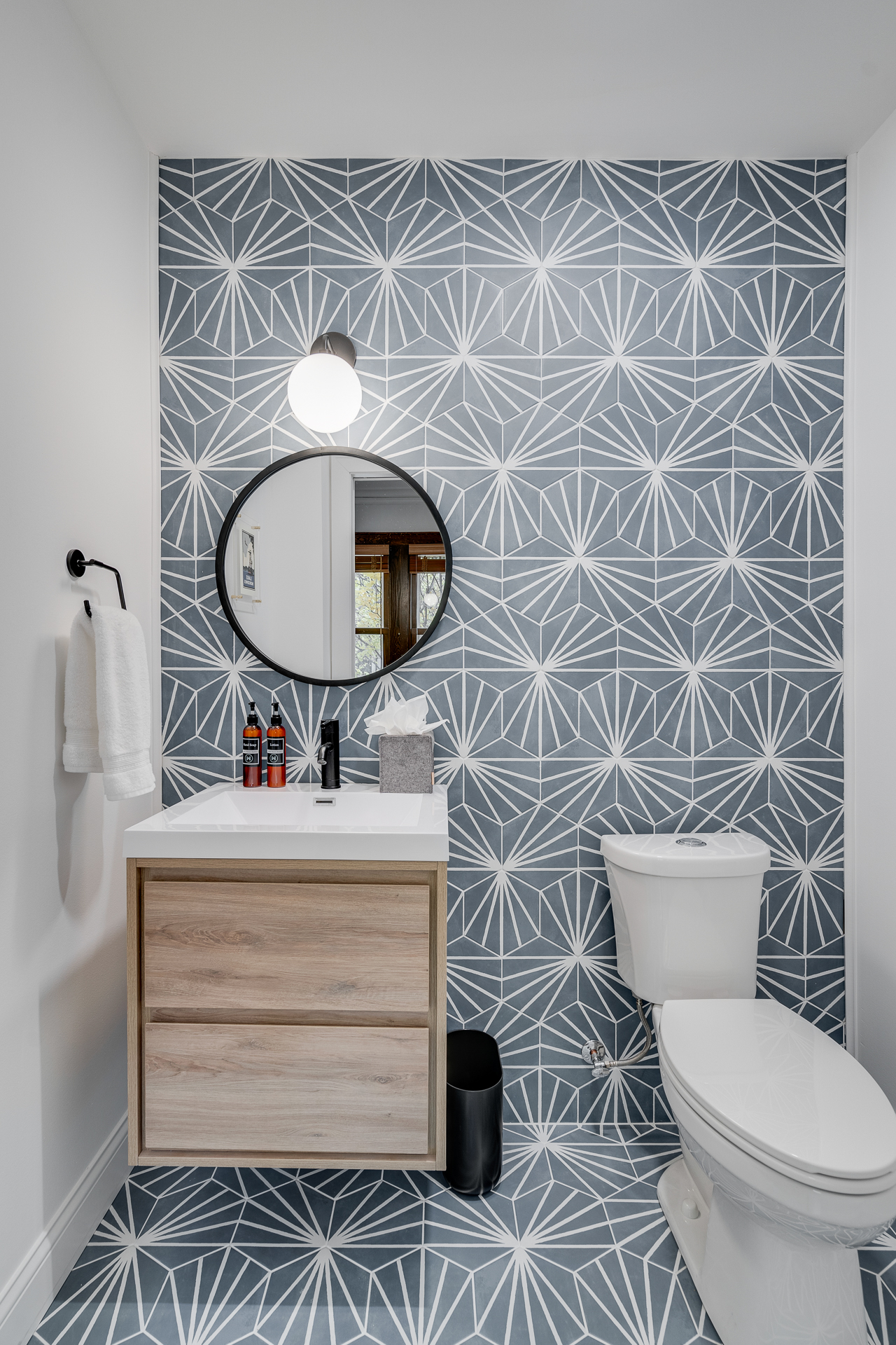 A modern bathroom featuring a geometric patterned wall and minimalist furnishings.