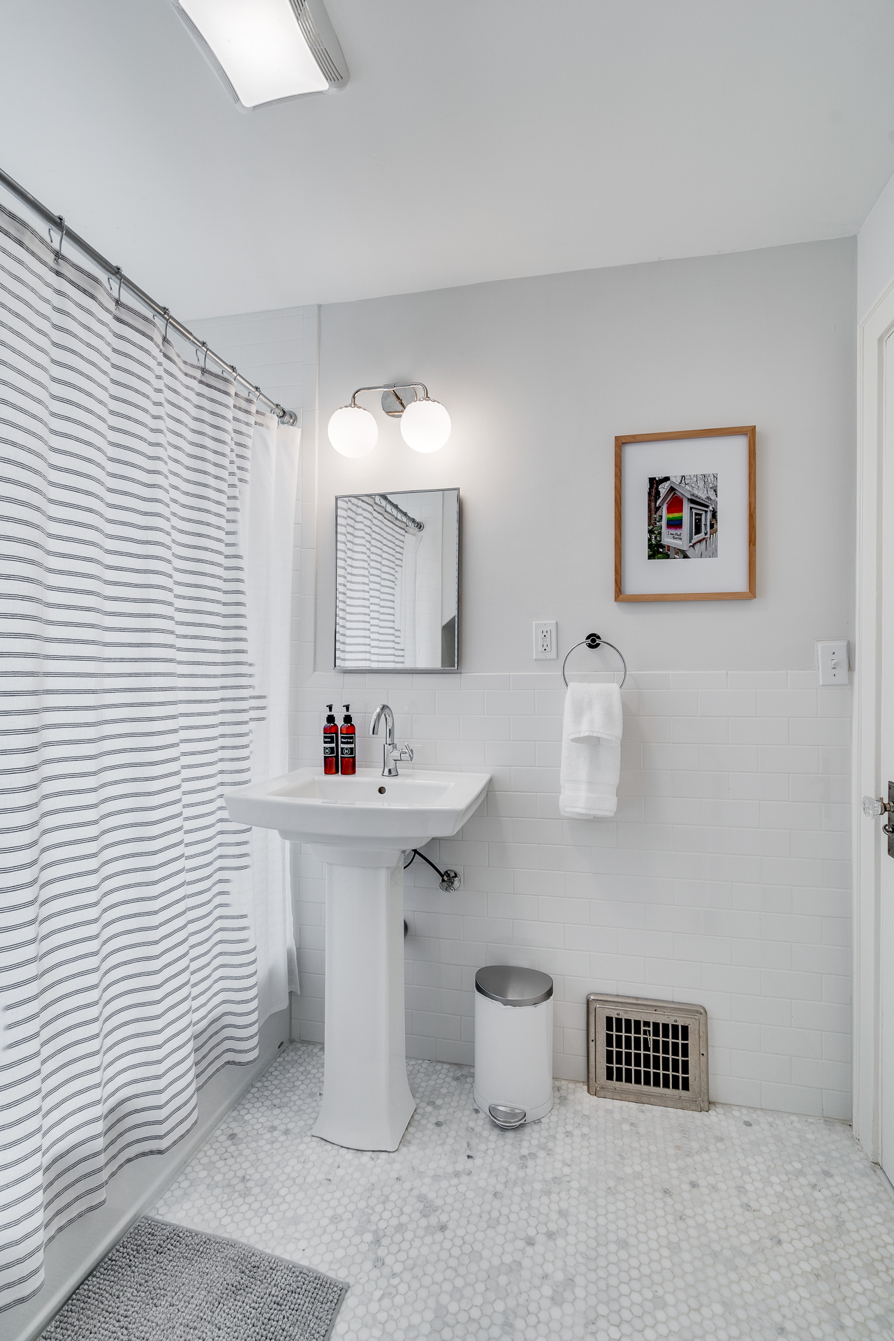 A sleek, modern bathroom with minimalist design elements, featuring a pedestal sink and stylish decor.