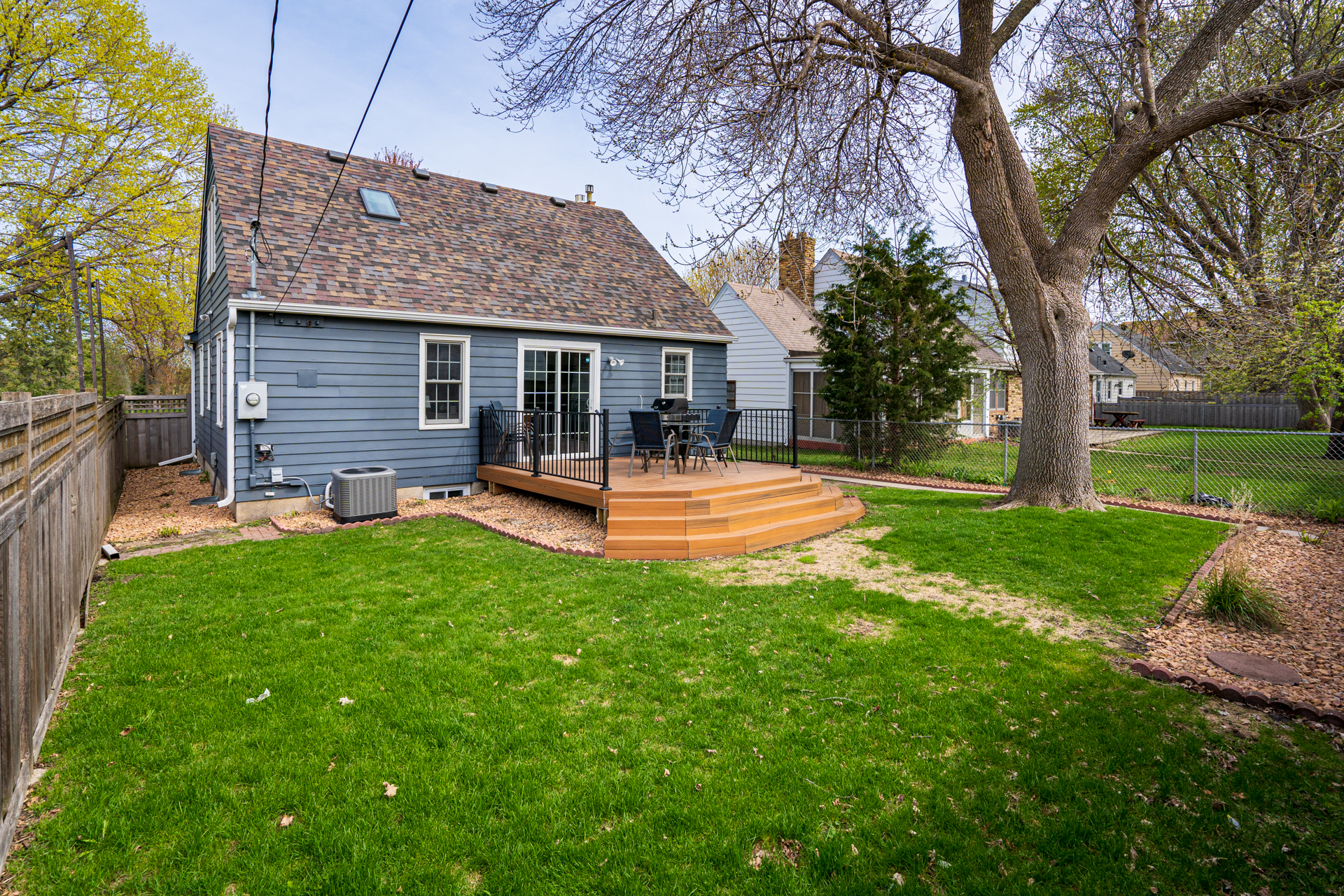 A cozy backyard featuring a wooden deck and lush green lawn, perfect for outdoor gatherings.