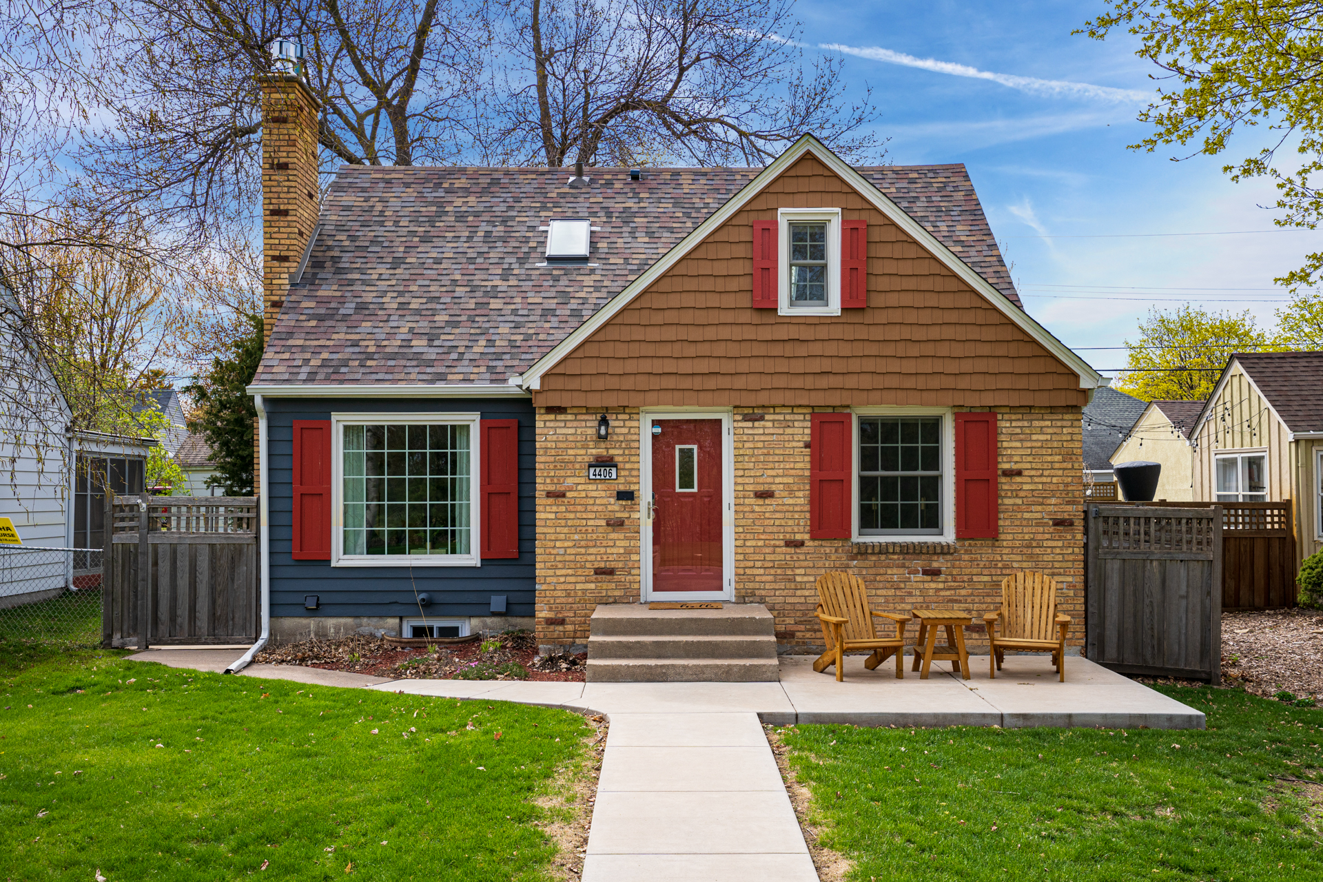 A charming two-story house with colorful accents and cozy outdoor seating.