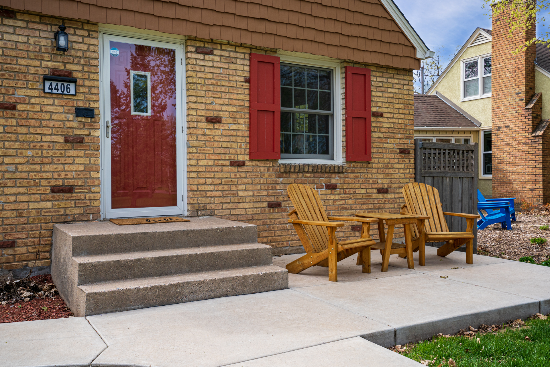 Welcoming entrance featuring a red door and rustic wooden chairs.
