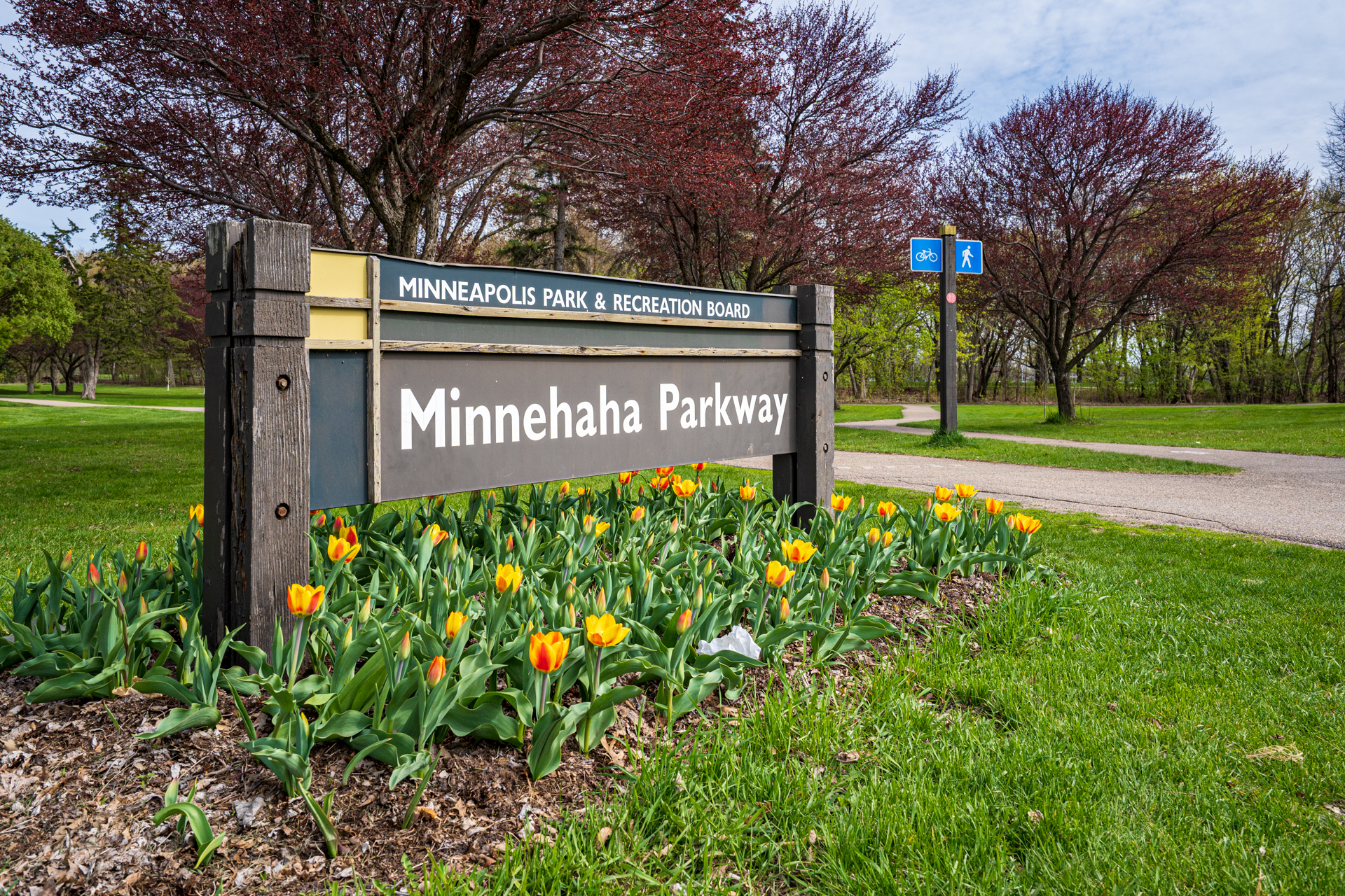 Welcoming entrance to Minnehaha Parkway with blooming tulips and park signs.