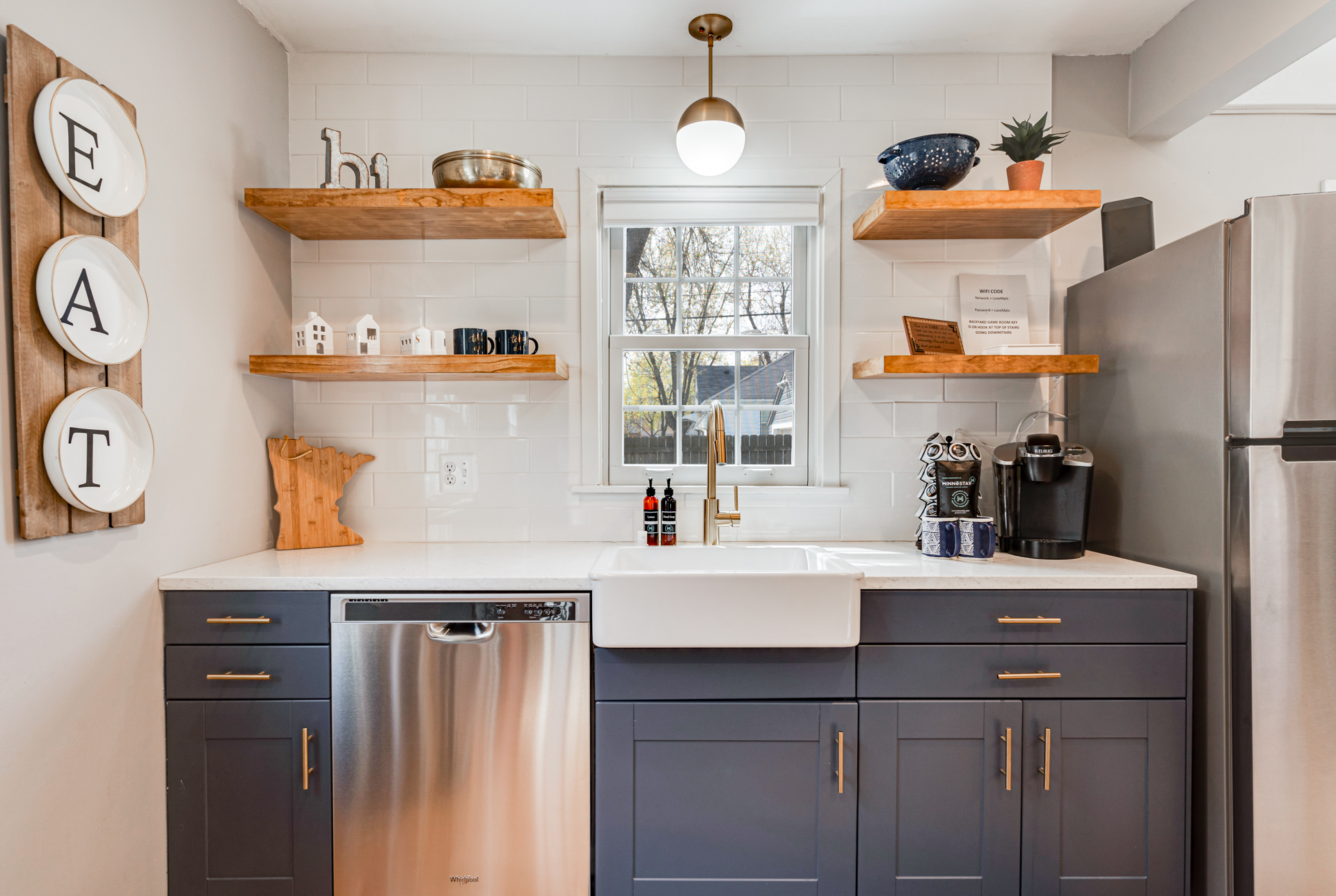 A modern kitchen with navy cabinets and a farmhouse sink.