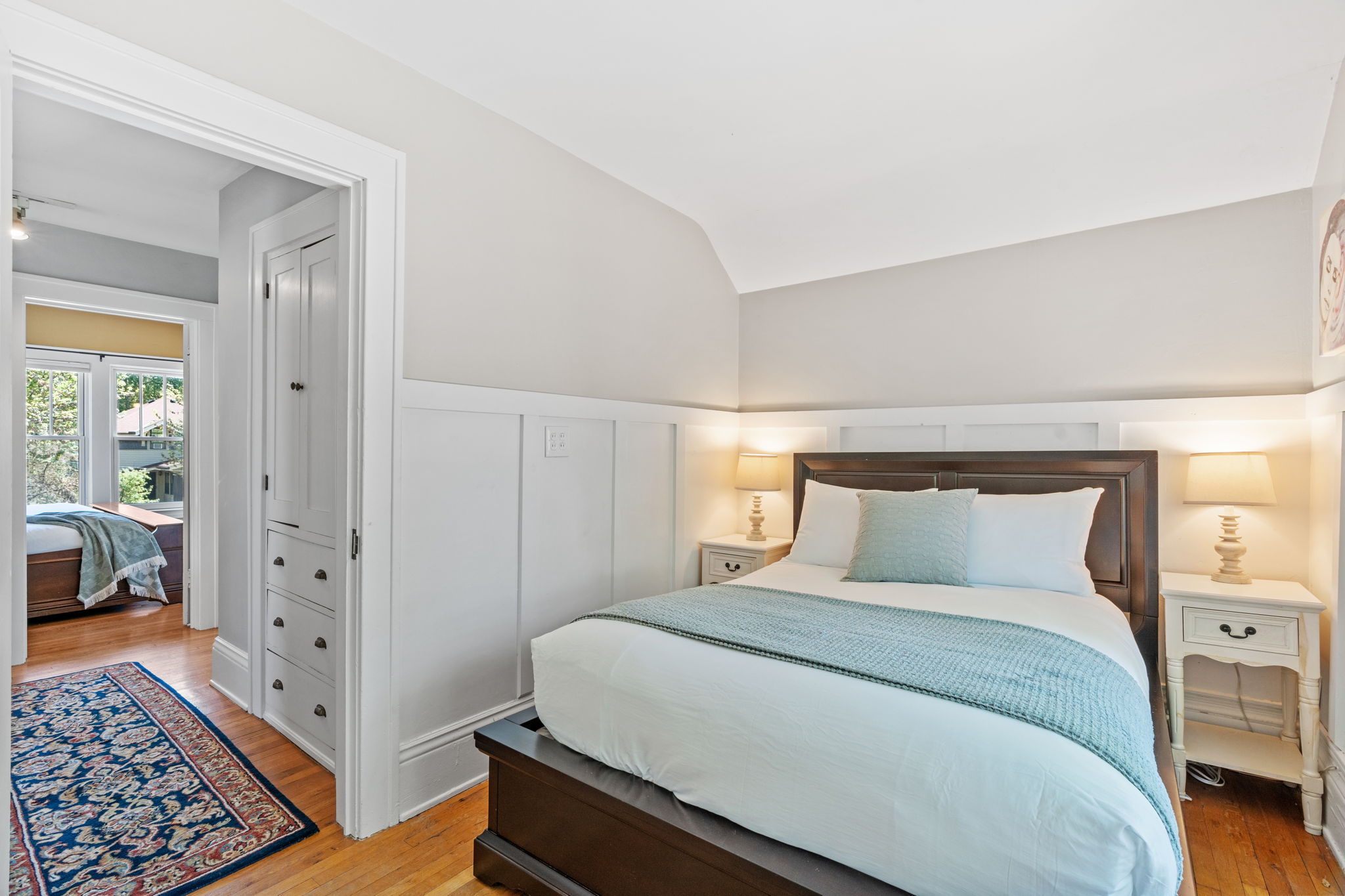 A cozy and bright bedroom with neutral tones and wooden accents.