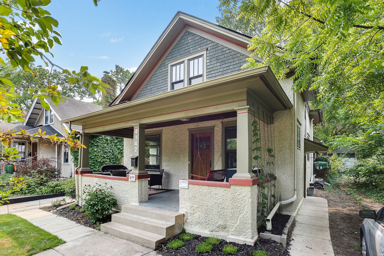 Charming two-story house with inviting porch and lush surroundings.