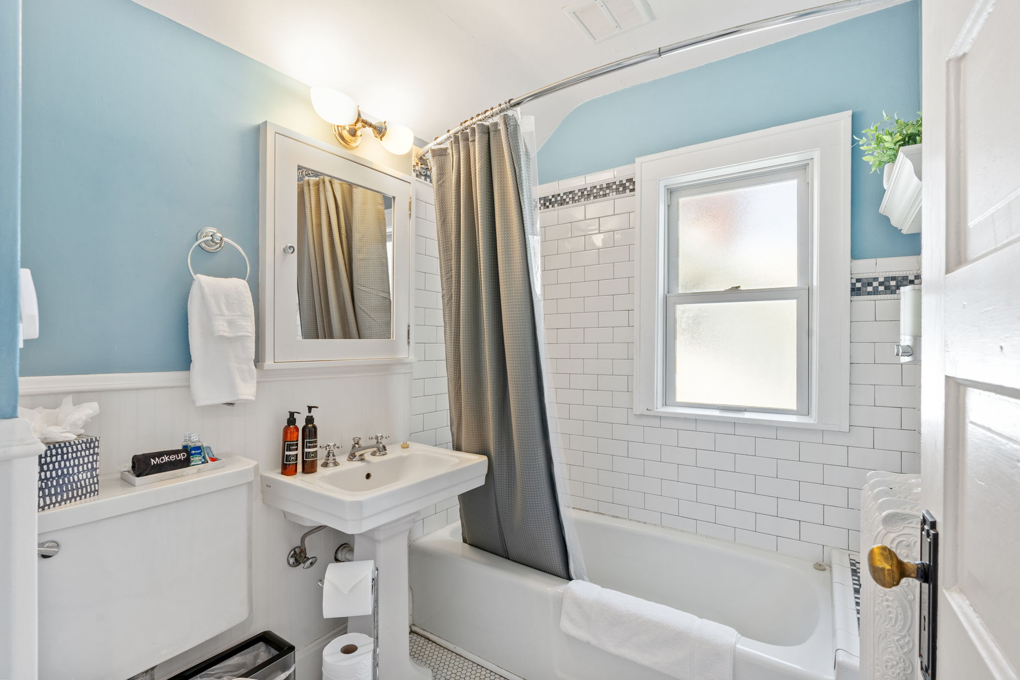 Bright and inviting bathroom with a classic design featuring blue walls and white tiles.