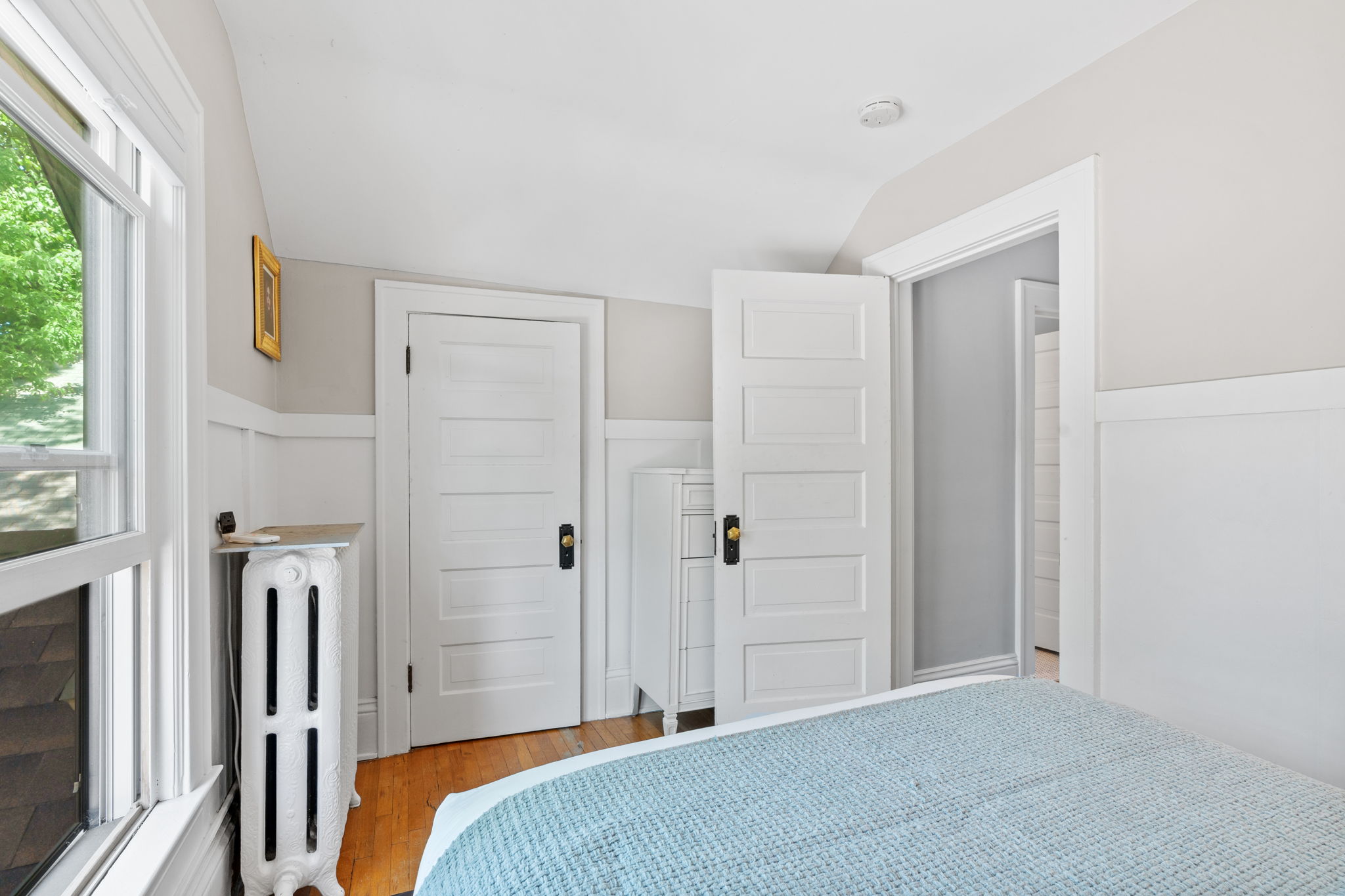 A cozy bedroom featuring soft beige walls, white trim, and a blue blanket on the bed.