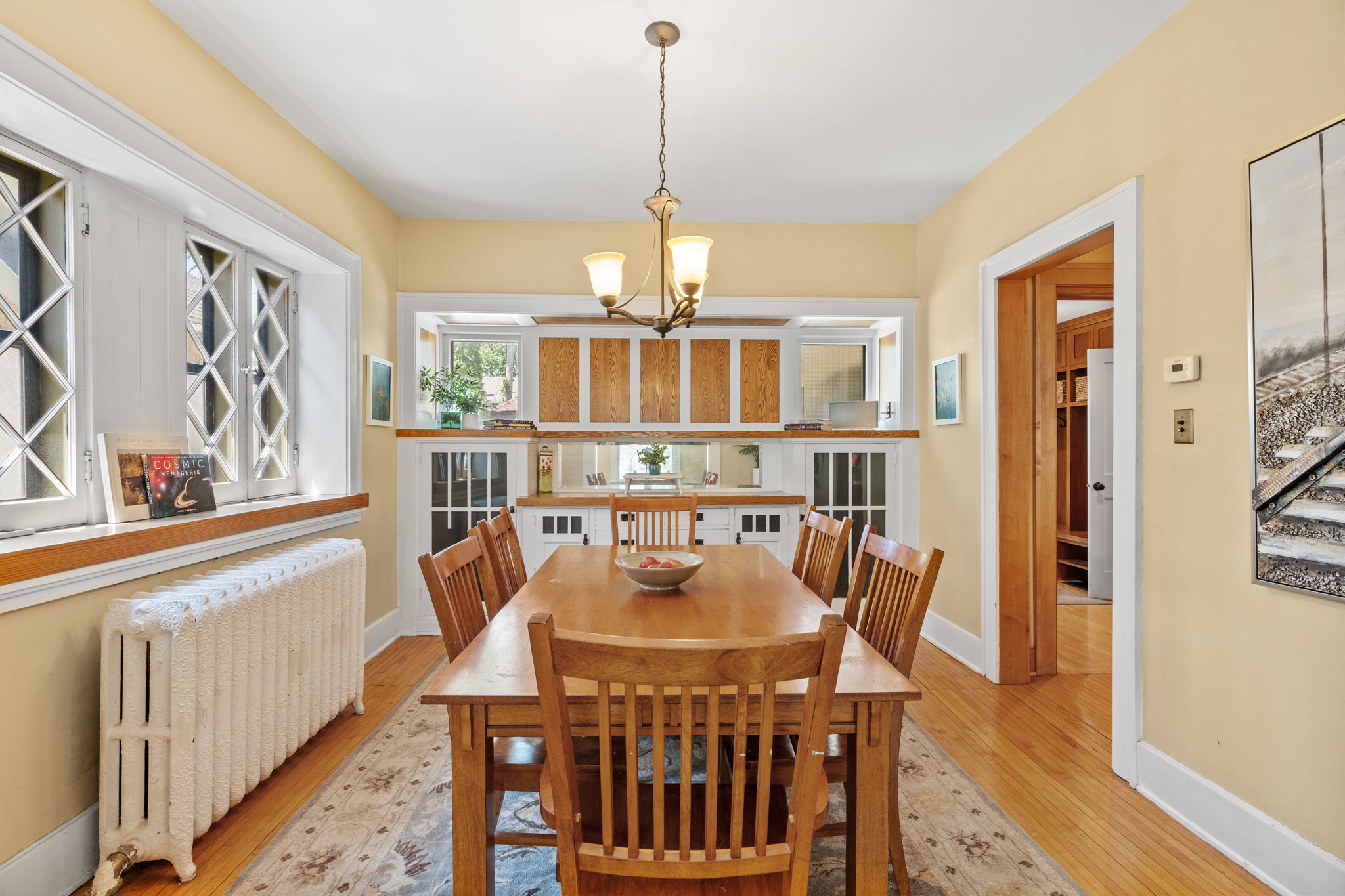 A cozy dining room illuminated by natural light with a long wooden table and chairs.