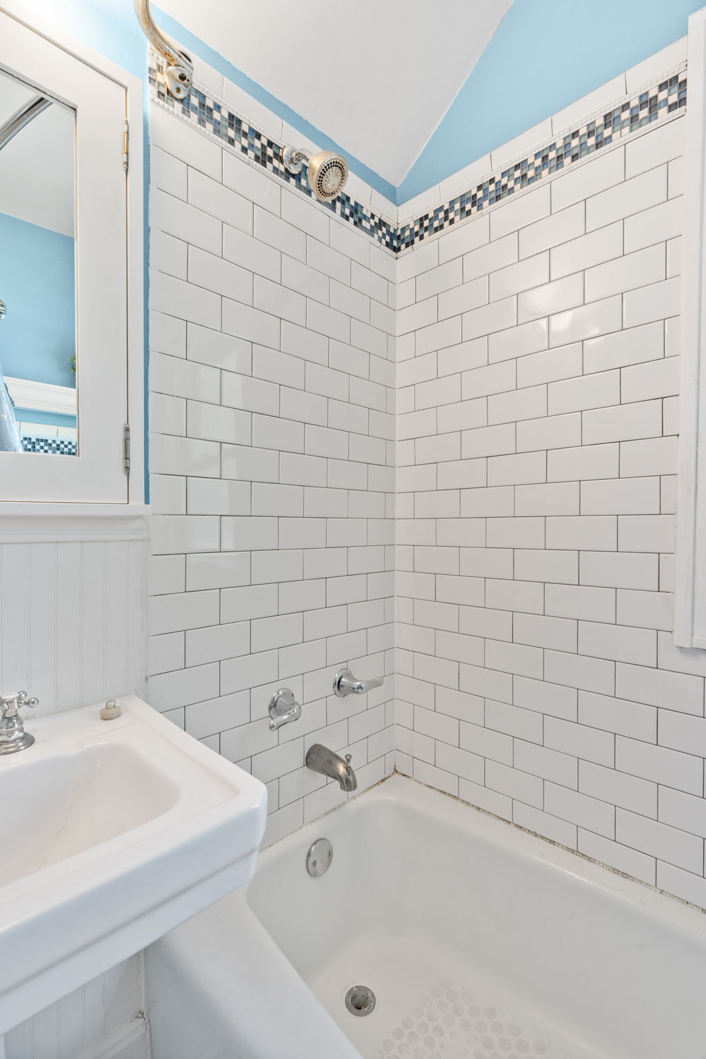 A clean and modern bathroom featuring white subway tiles and a decorative tile border.