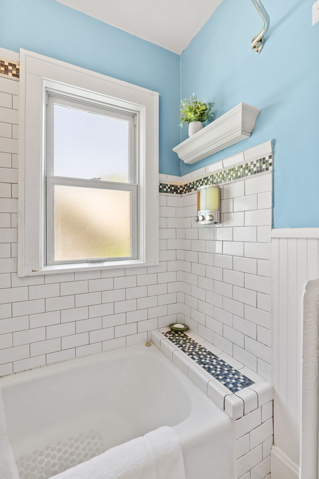 A serene bathroom corner with soft blue walls and white tile accents.