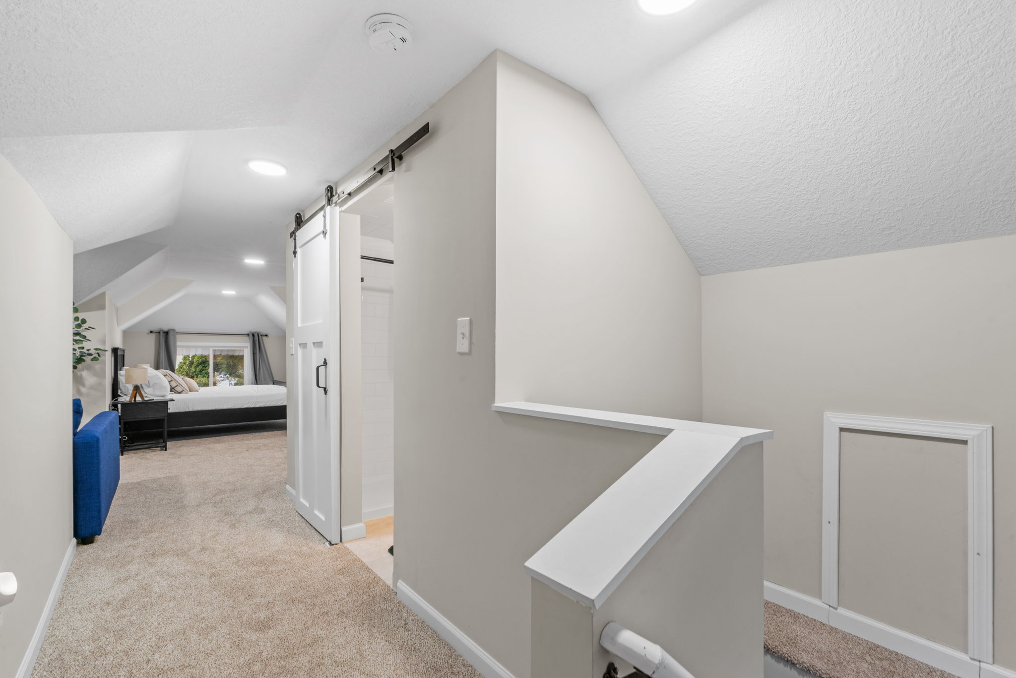 A stylish hallway leading to a cozy upper-level bedroom and bathroom.