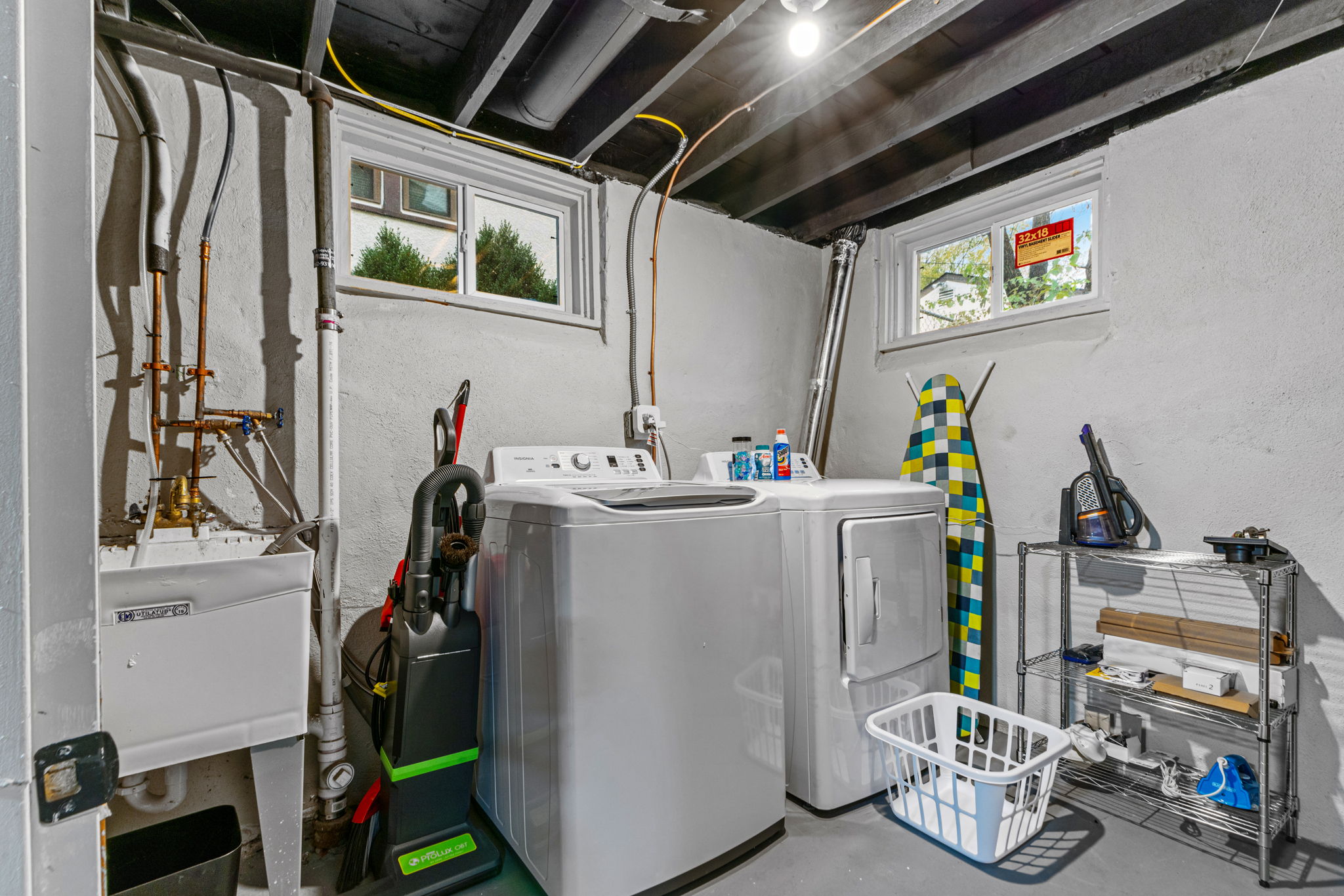 A modern laundry room featuring washing and drying appliances against a clean gray backdrop.