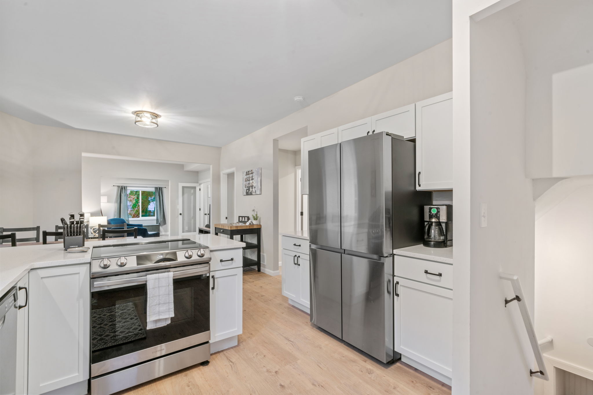 A modern kitchen with stainless steel appliances and white cabinetry, featuring a spacious and inviting design.