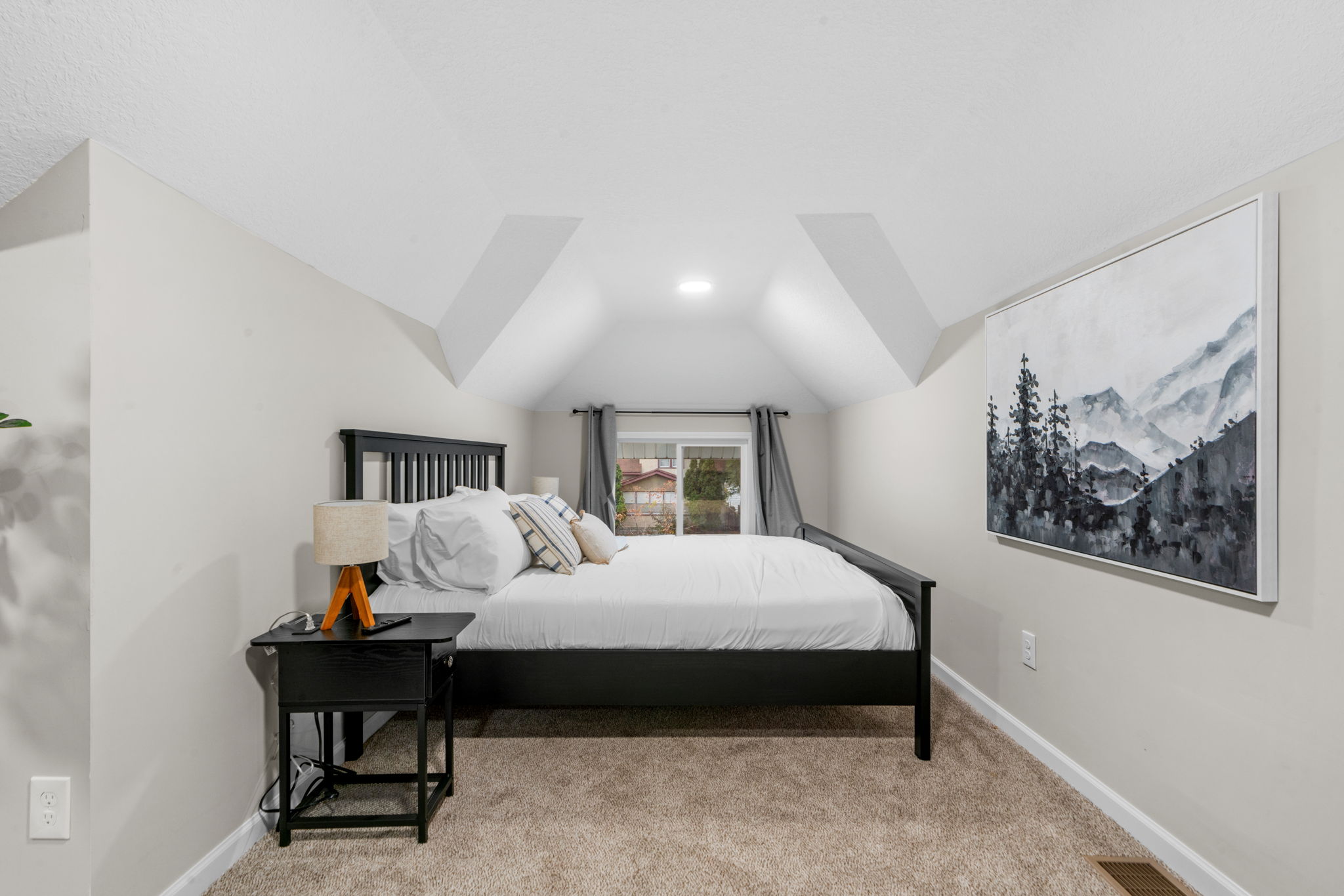 A cozy attic bedroom with sloped ceilings and a modern aesthetic.