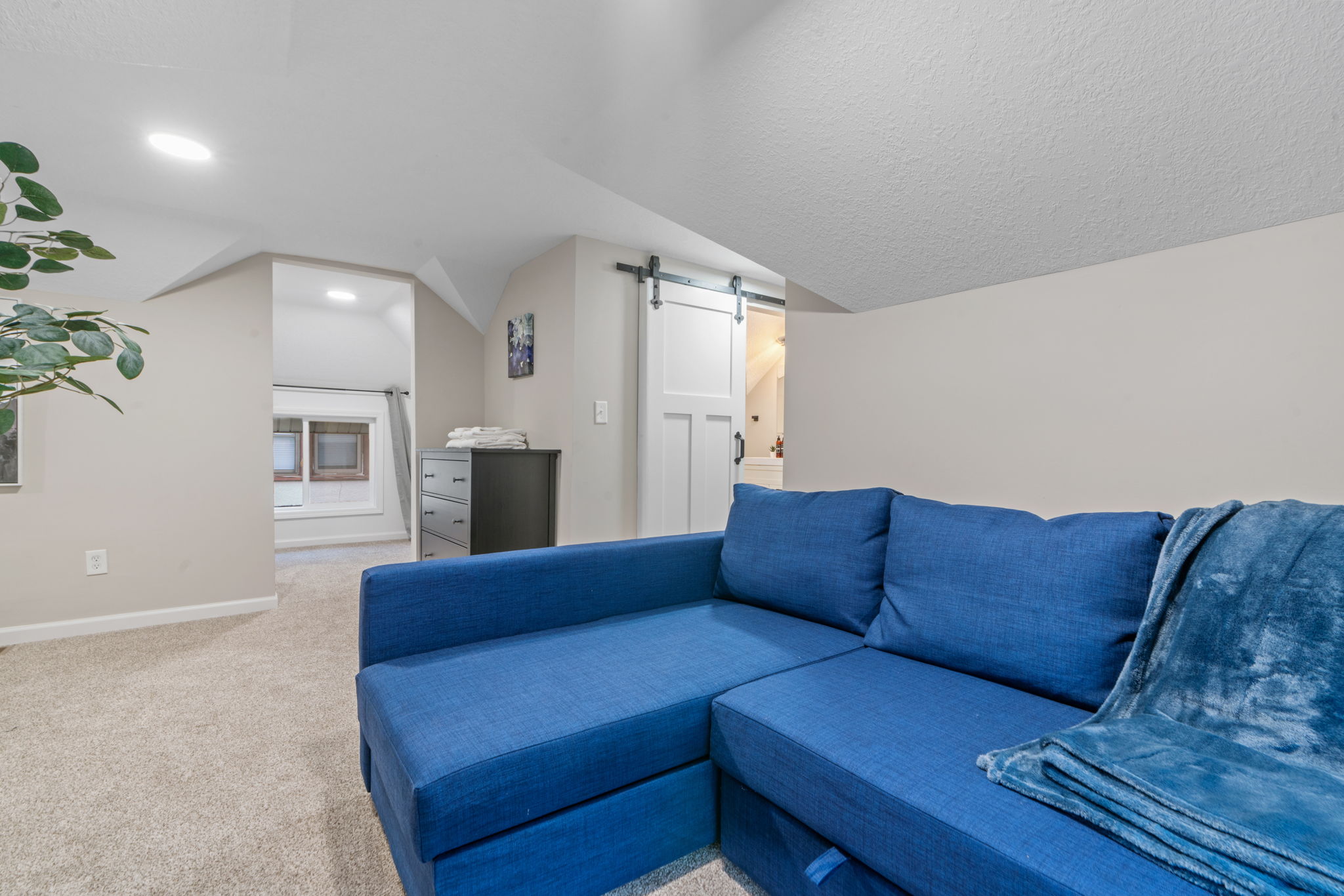 A cozy attic living space featuring a blue sofa and natural light.