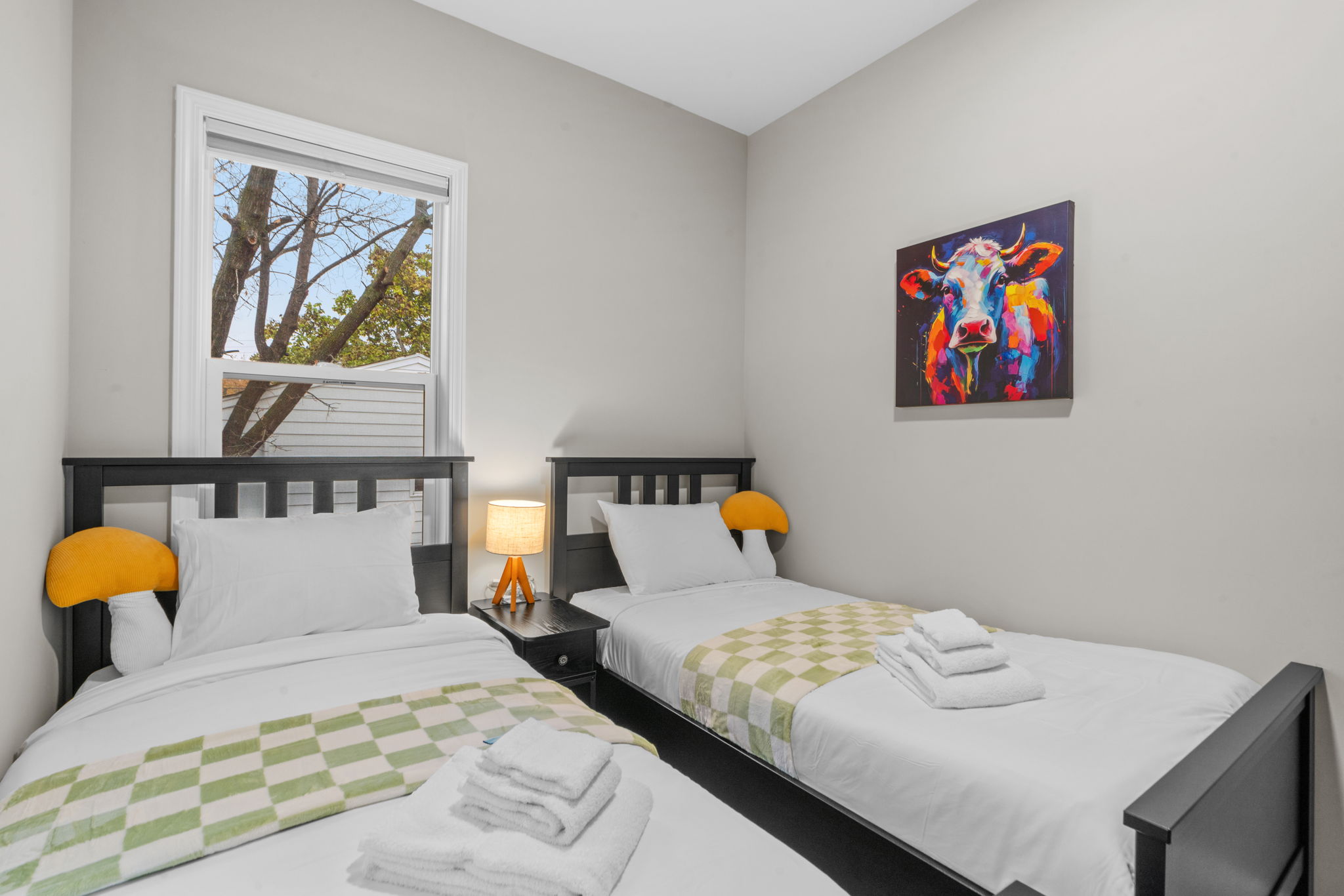 A cozy bedroom featuring two single beds with colorful accents and playful artwork.