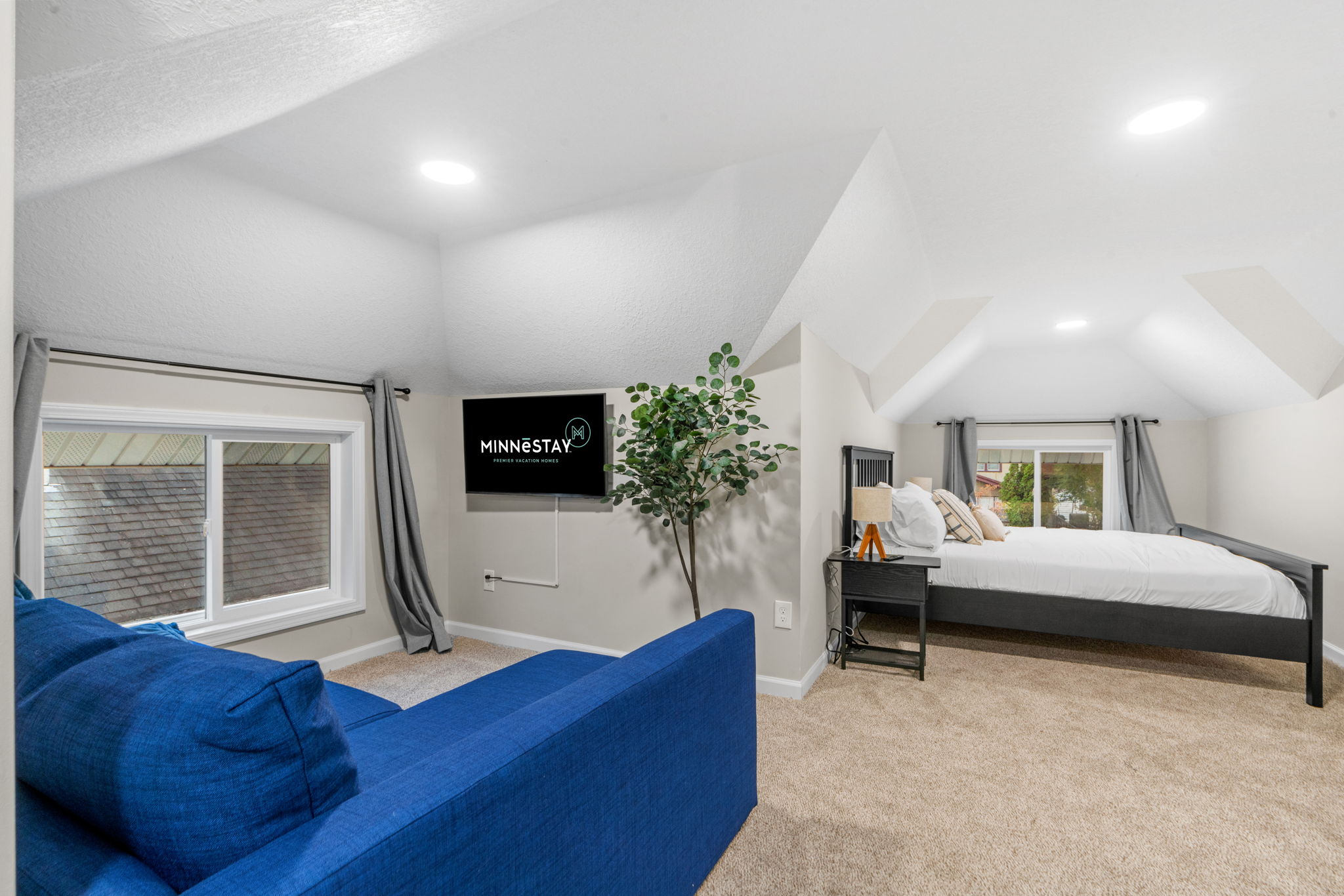 Cozy attic bedroom with modern decor and vibrant blue couch.