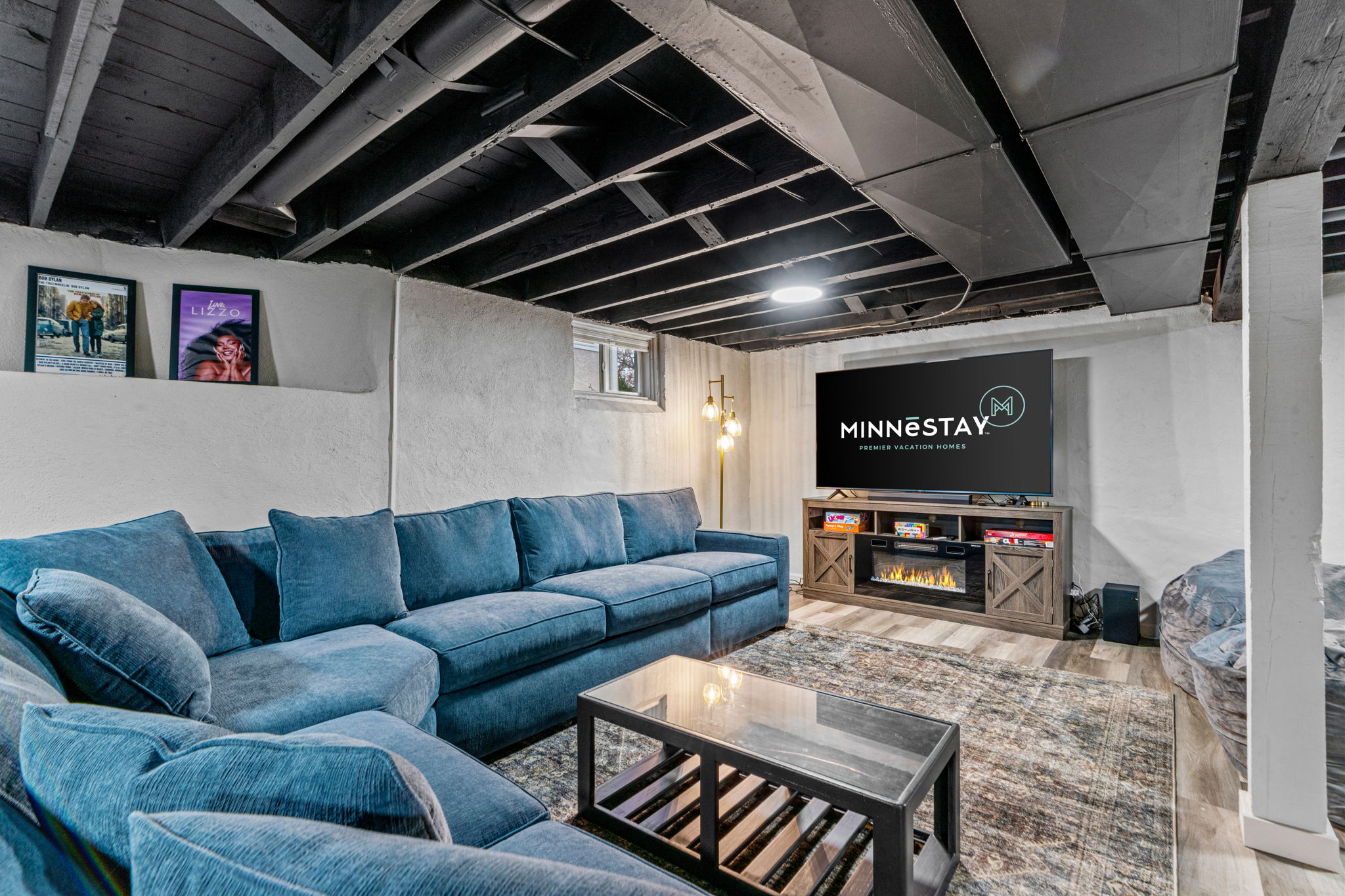 A modern basement living room setup featuring a plush blue sectional sofa and stylish decor.