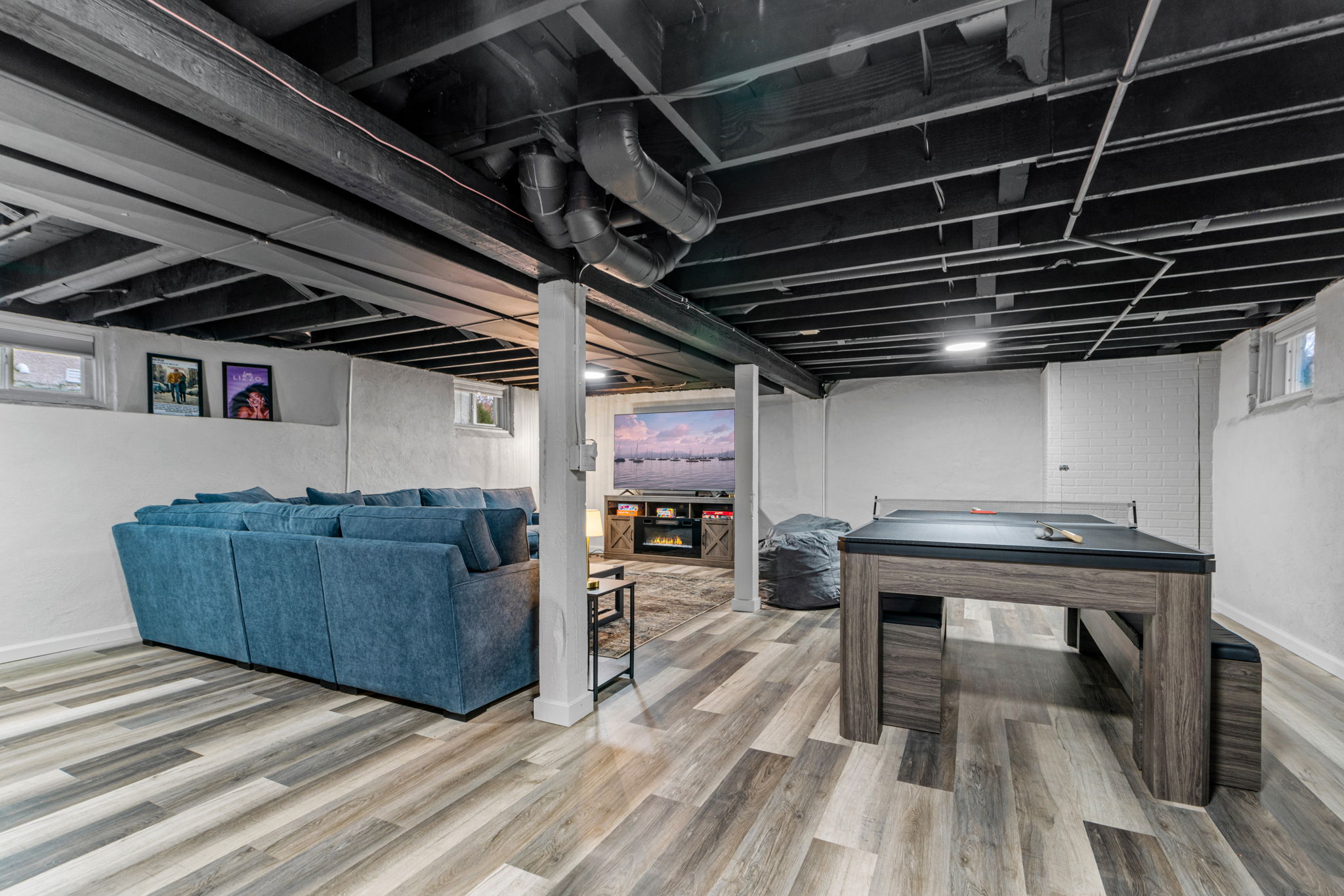 Modern basement living space with a cozy blue sofa and gaming table.