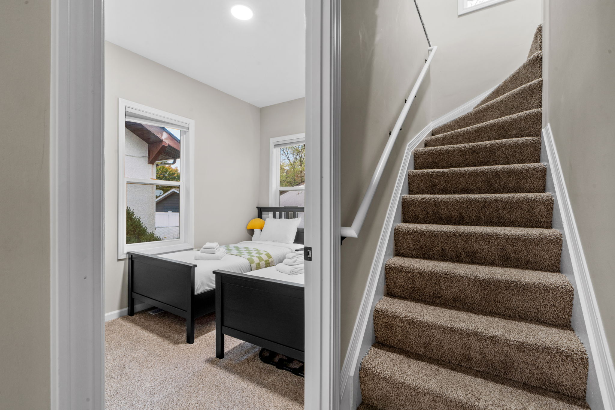 Cozy bedroom with two twin beds and inviting staircase.