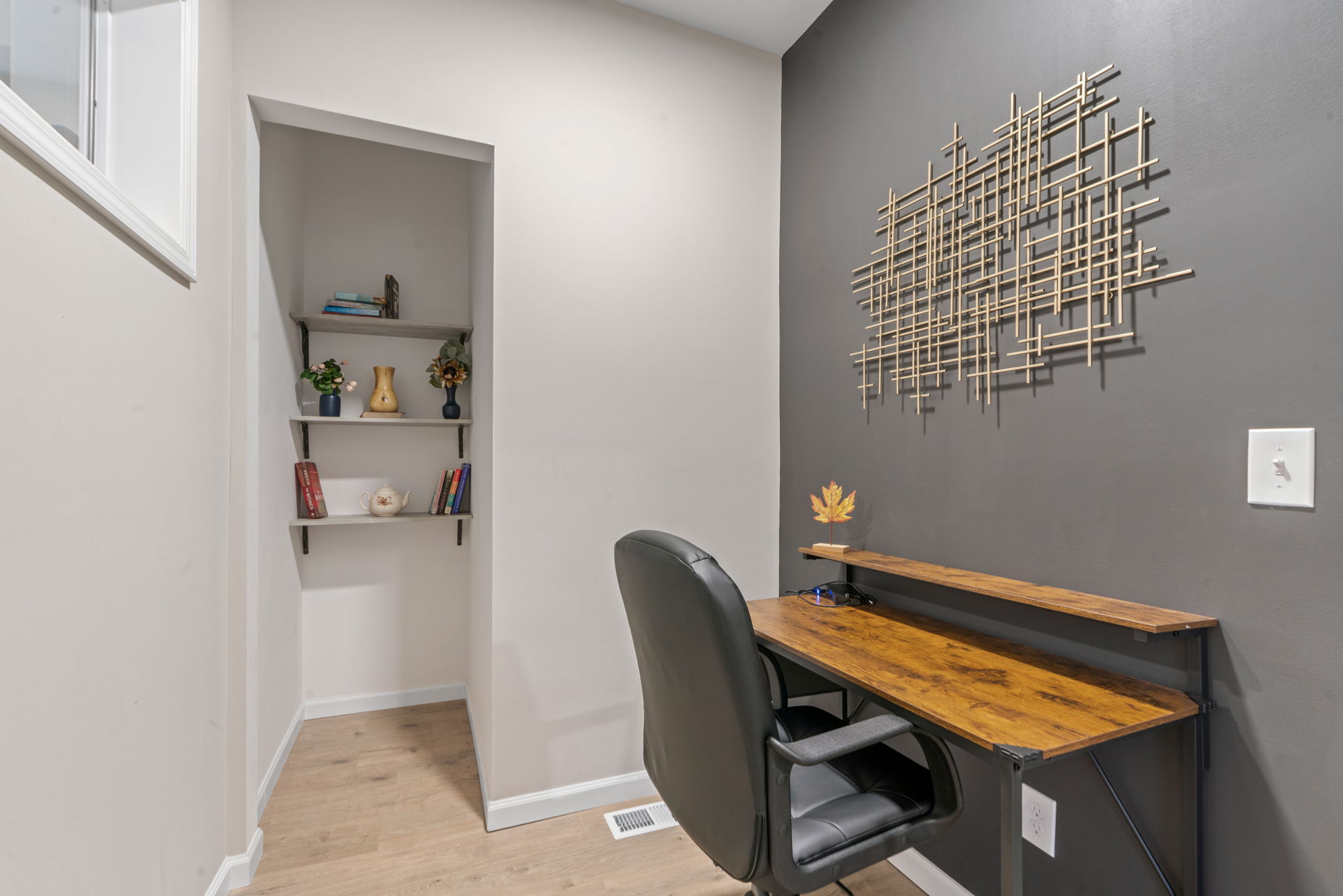 A minimalist workspace featuring a wooden desk, decorative shelving, and a comfortable chair.