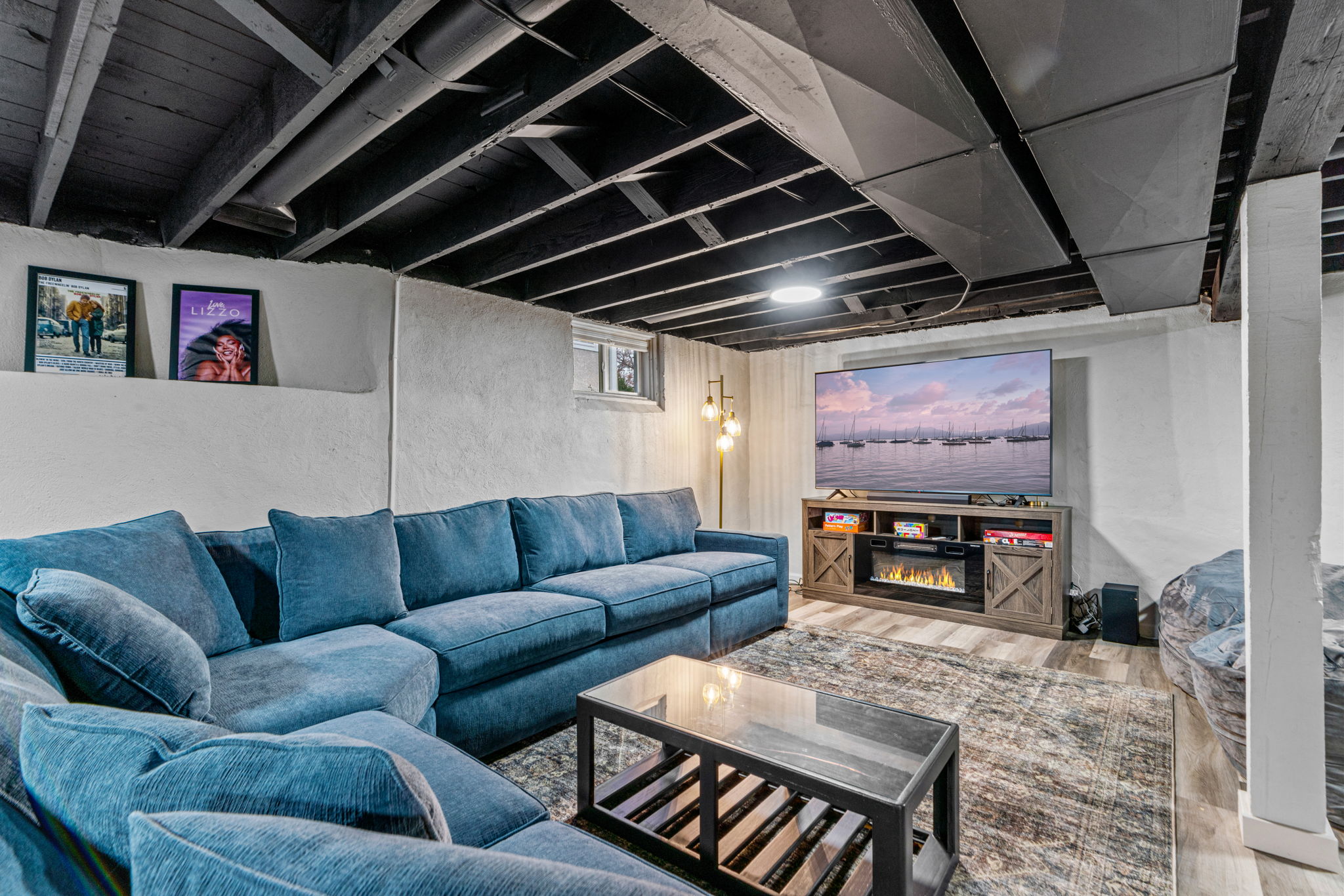 Cozy and modern basement living room with blue sectional and TV.