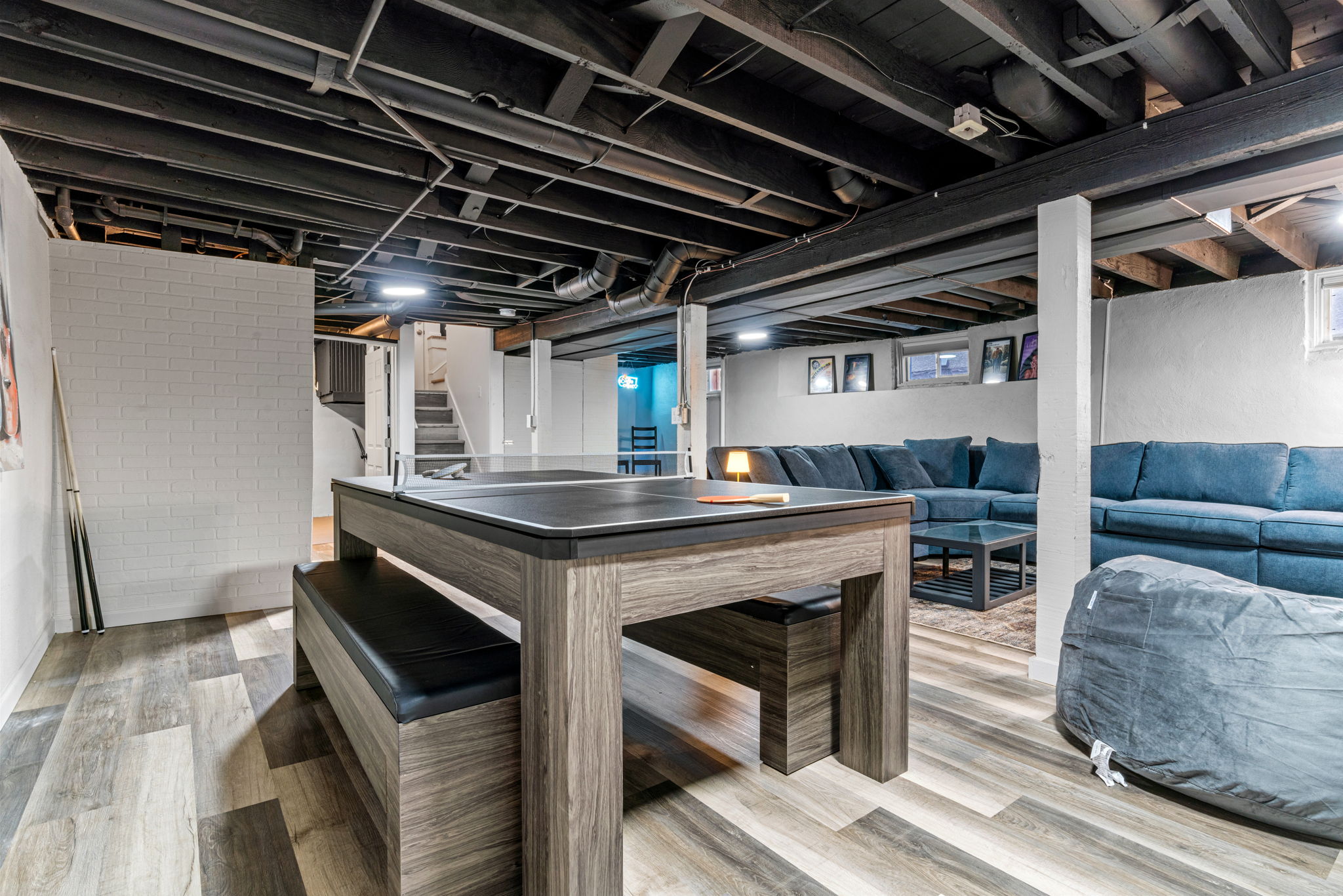 A stylish basement with a ping pong table and a cozy seating area.